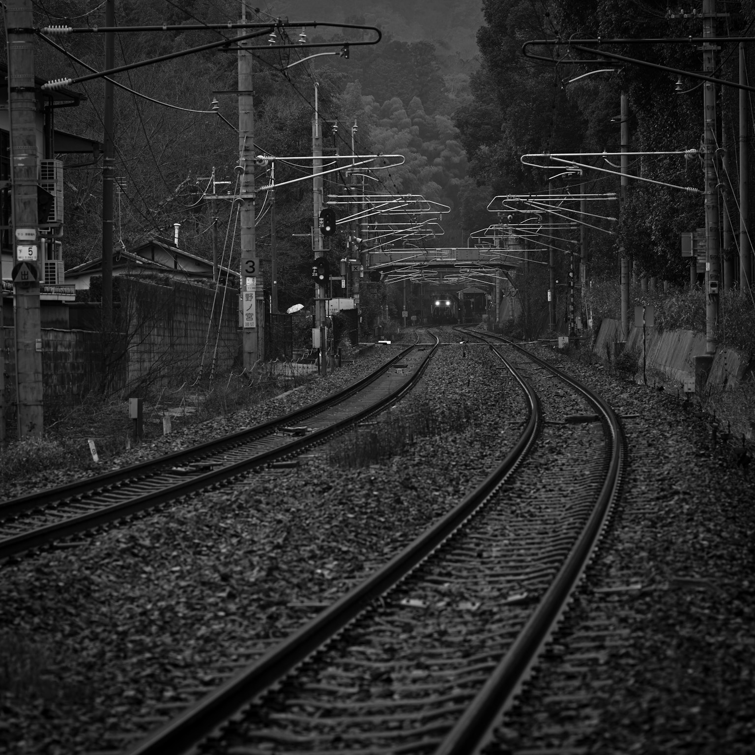 Jalur kereta api melengkung dengan kabel overhead dalam pengaturan monokrom