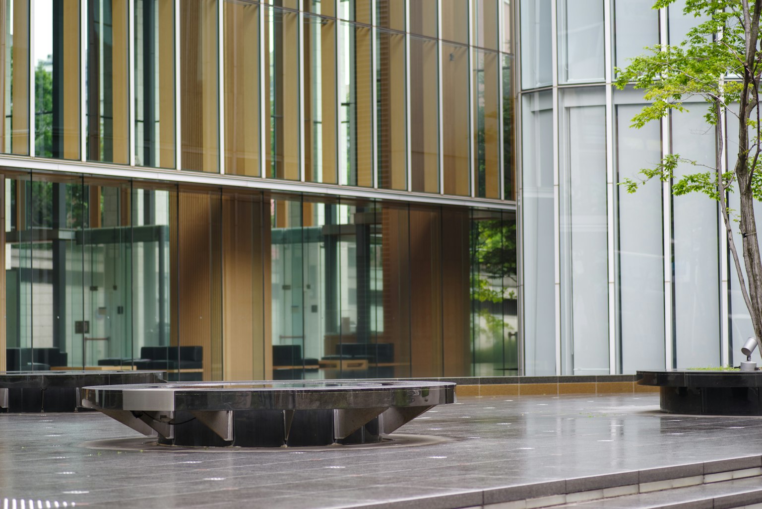 Extérieur d'un bâtiment moderne avec des éléments en verre et en bois avec un banc de plaza
