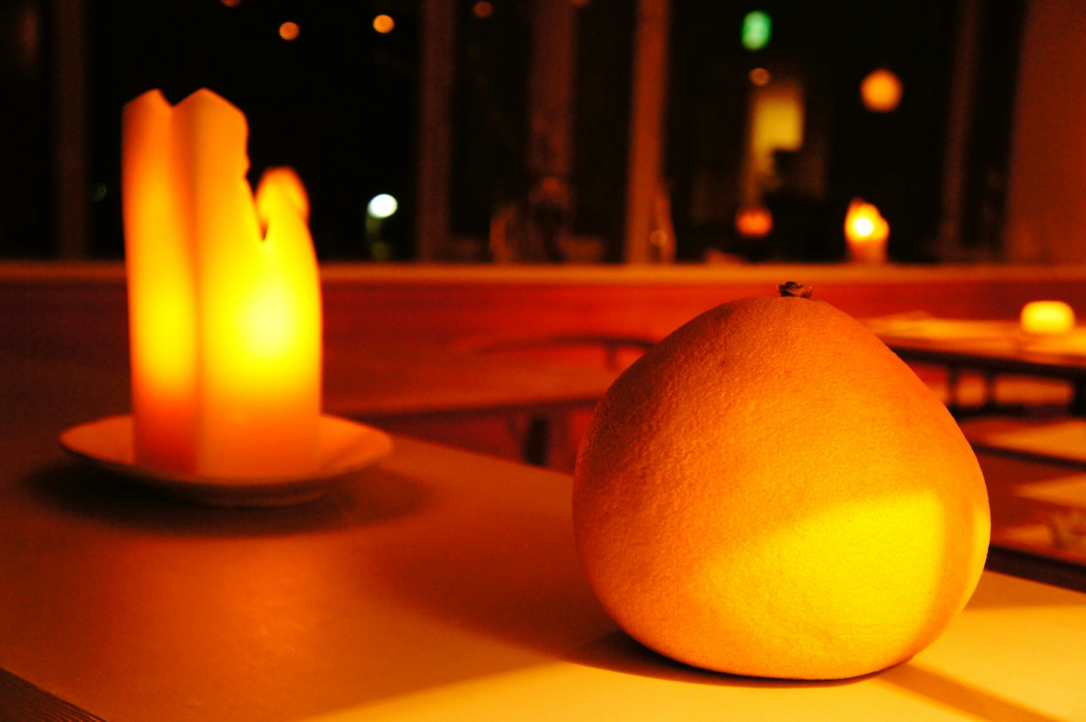 Buah oranye di samping lilin bercahaya dalam pencahayaan hangat