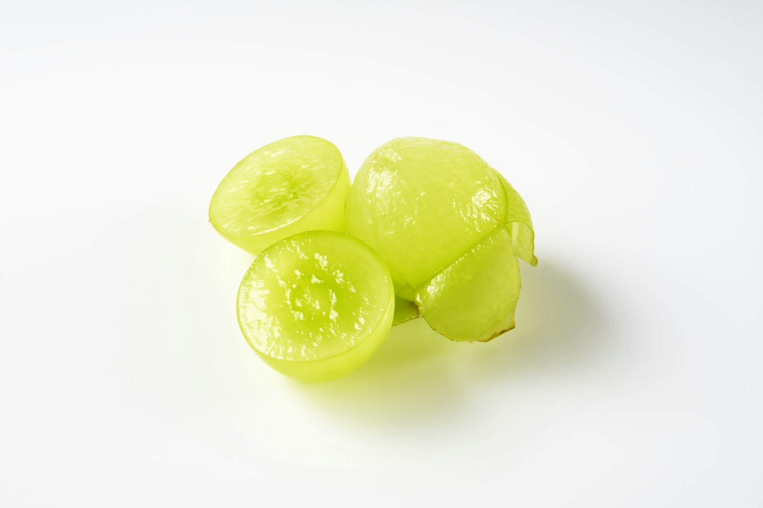 Uvas verdes claras con una cortada a la mitad mostrando el interior