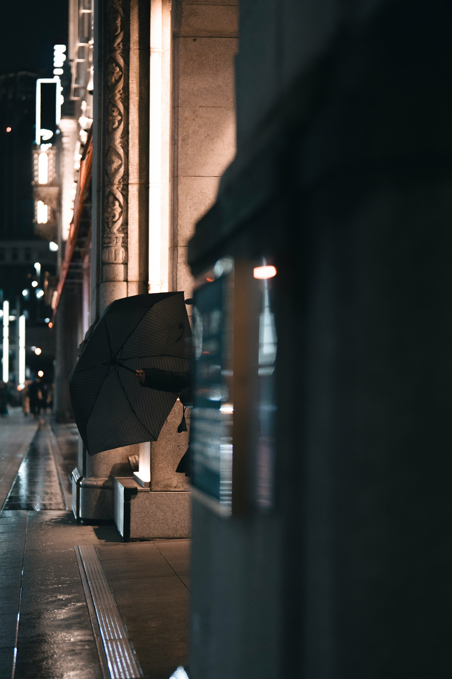 Un ombrello nero è posizionato all'angolo di una strada di notte