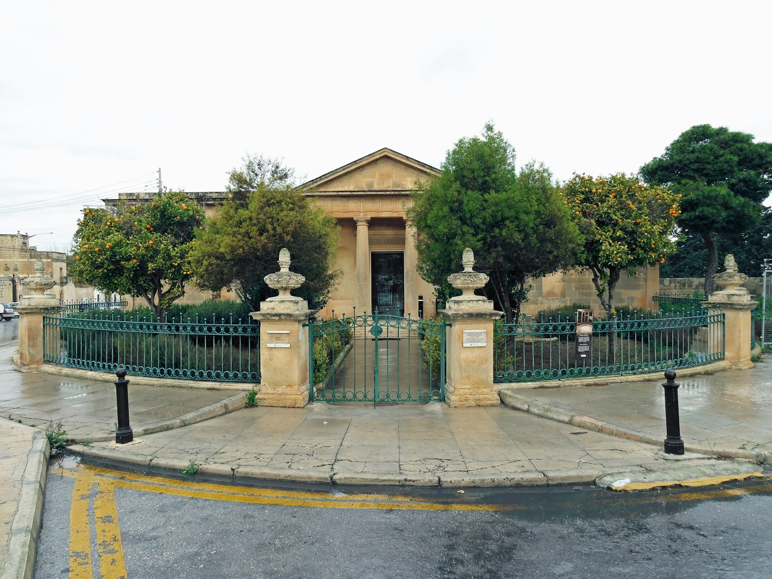 Edificio in pietra con un giardino lussureggiante e una recinzione decorativa