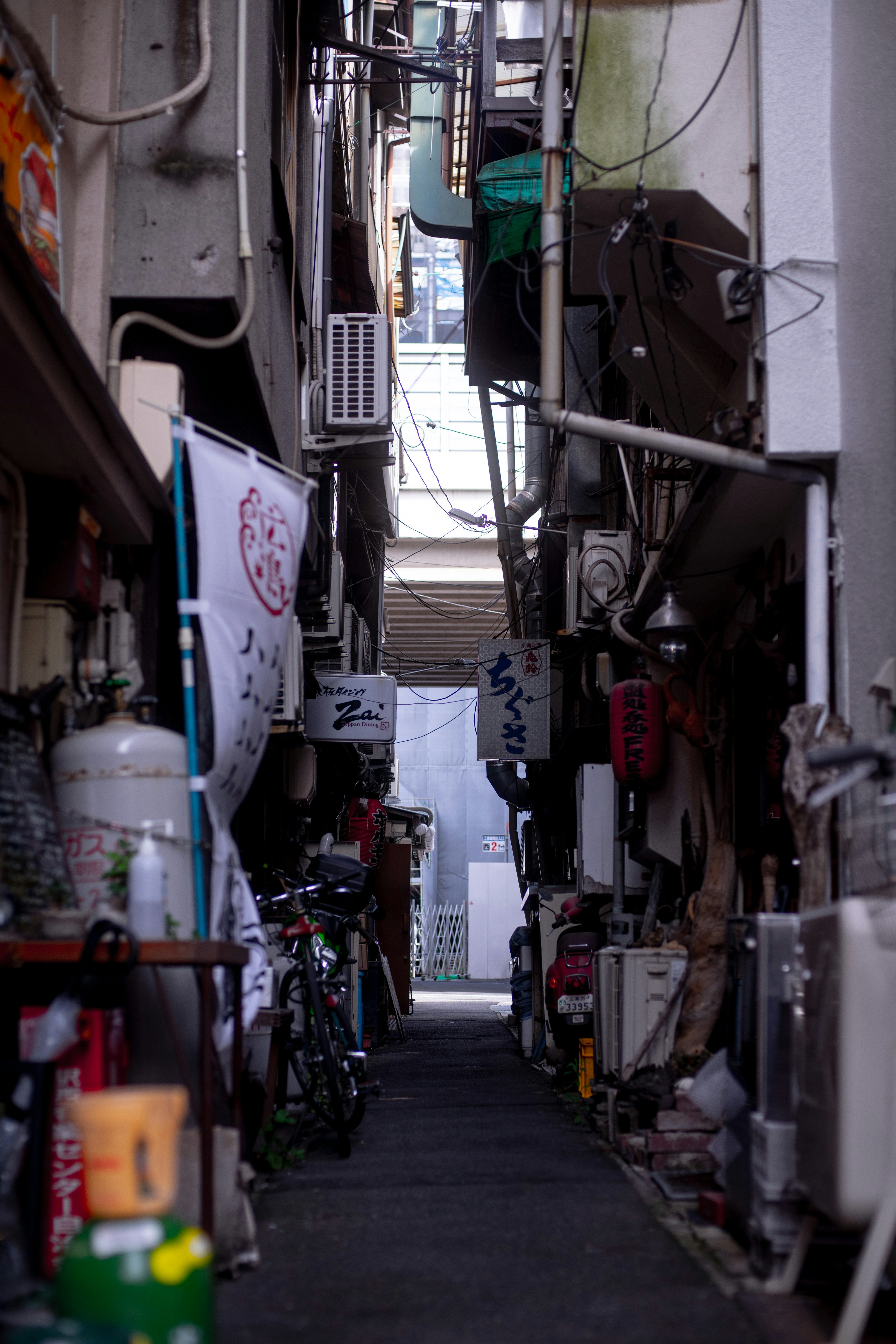 路地に並ぶ自転車と店先の細い通路