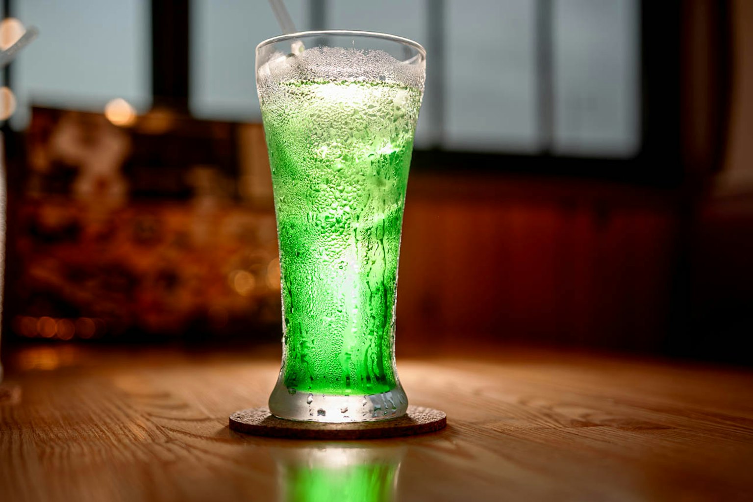 一個透明的杯子裡裝滿了綠色的碳酸飲料和泡沫