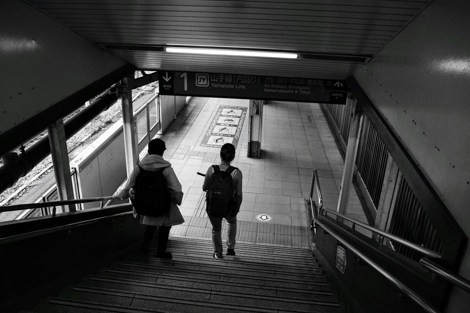 Dos personas bajando escaleras en una estación de tren