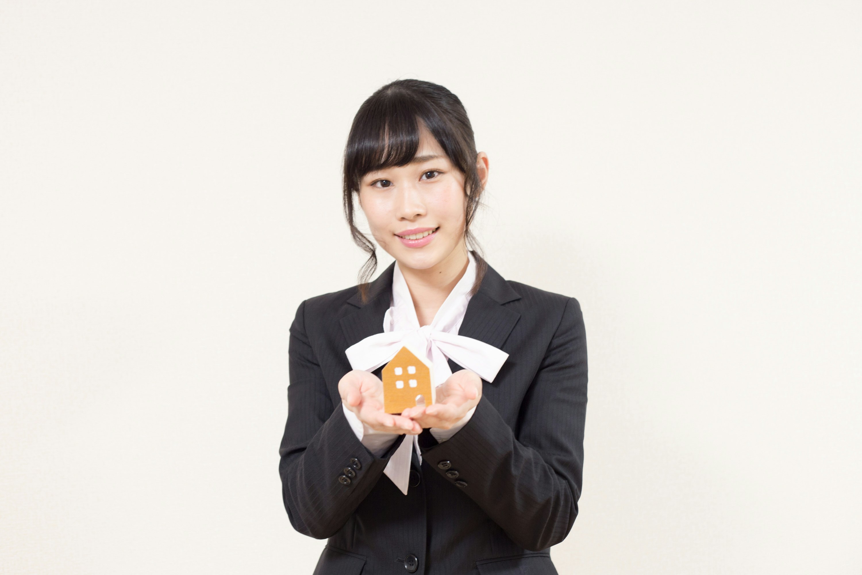 穿西裝的女性手持房屋形狀道具