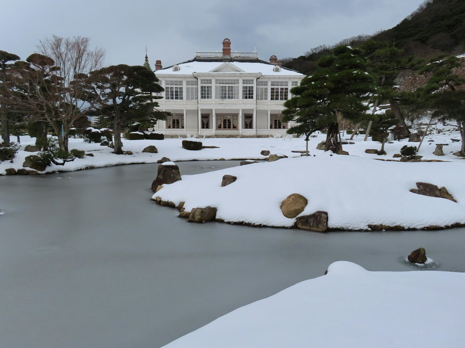 Vue pittoresque d'un beau manoir blanc près d'un étang enneigé