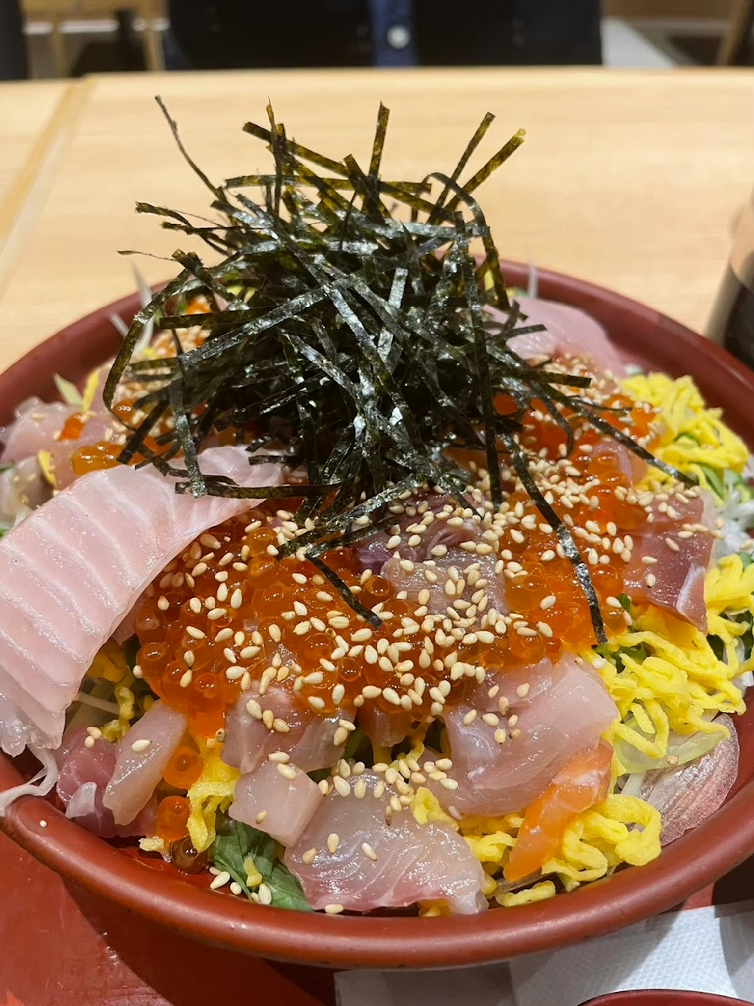 Una ciotola colorata di sashimi con riso guarnita con alga