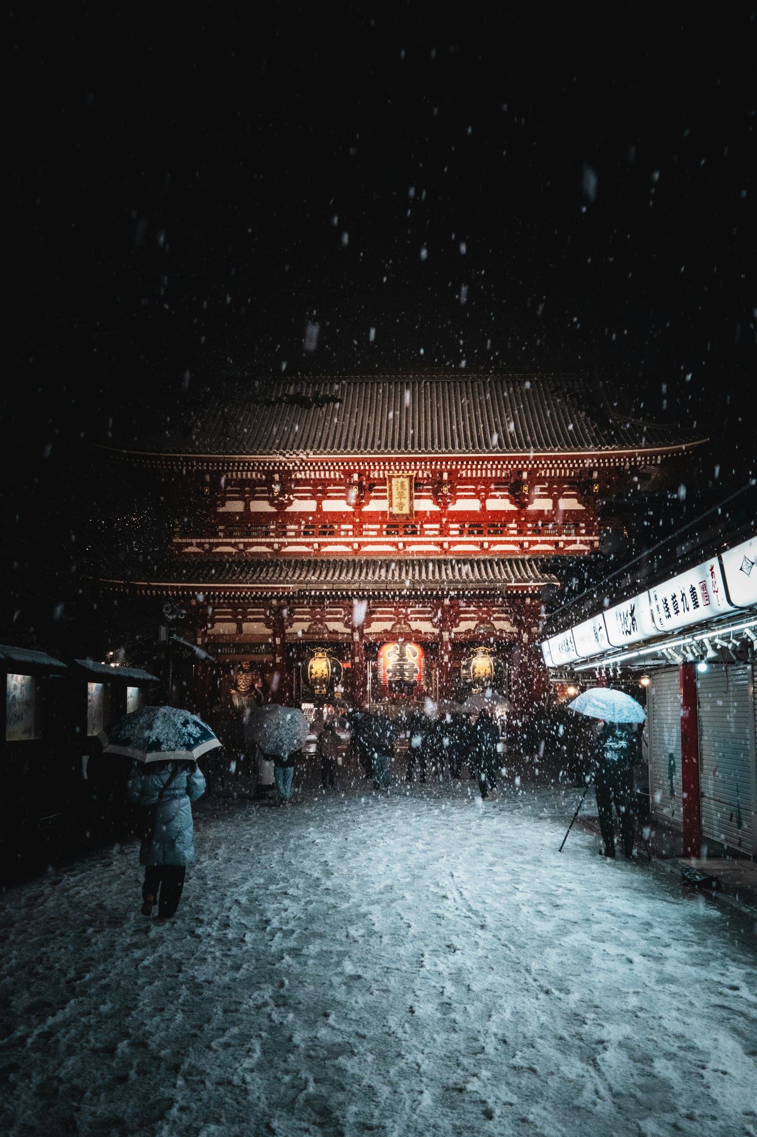 雪中的寺廟門和打傘的人們