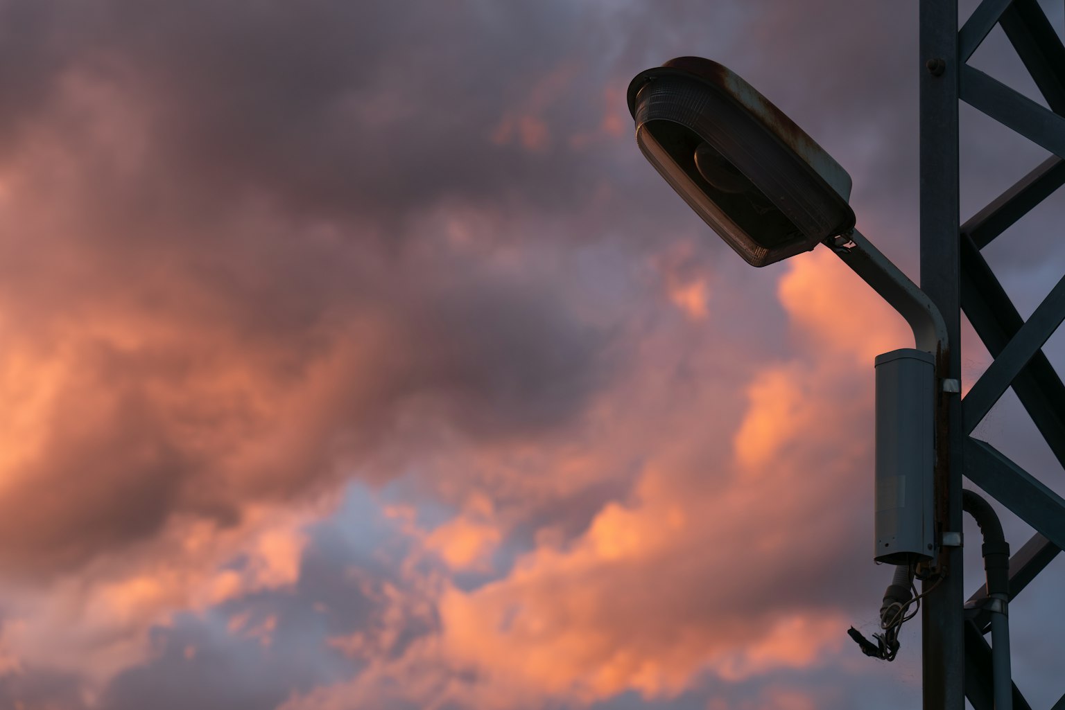 Farola junto a una torre de metal contra un cielo de atardecer