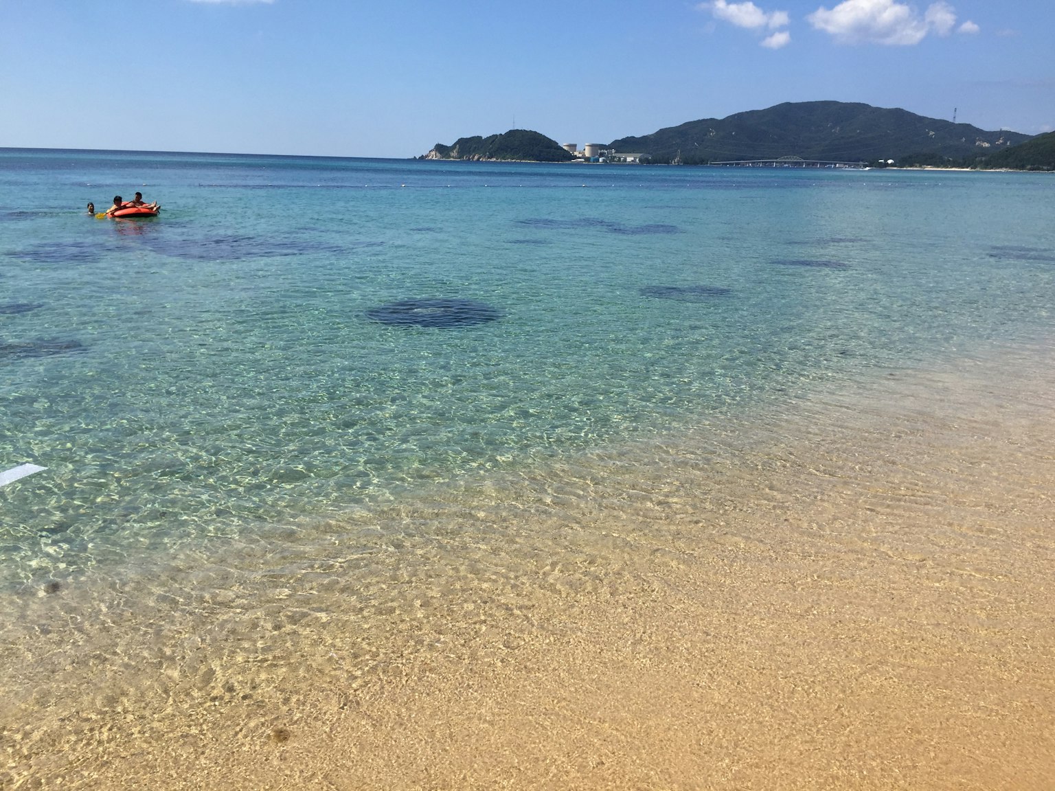 Agua del océano clara y playa de arena con un pequeño bote