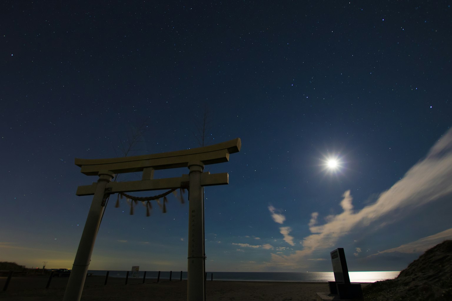 Puerta torii bajo un cielo nocturno con luna llena