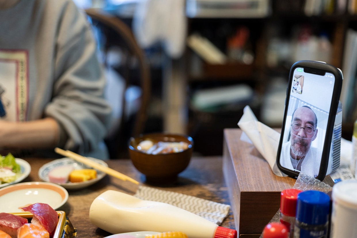 食卓でスマホ越しにオンライン通話する家族の食事シーン