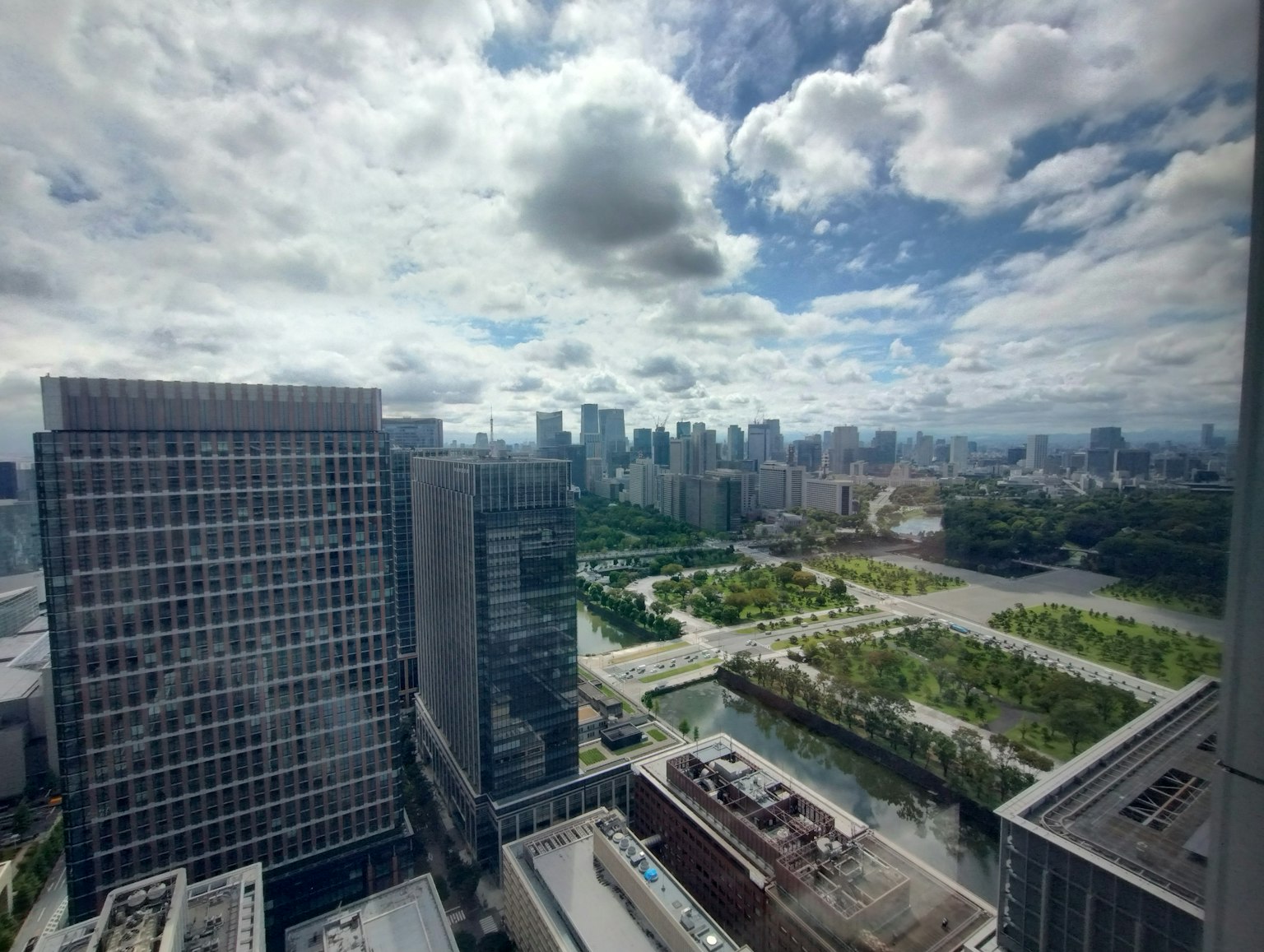Vue d'un bâtiment de grande hauteur montrant un parc verdoyant et la ligne d'horizon de la ville