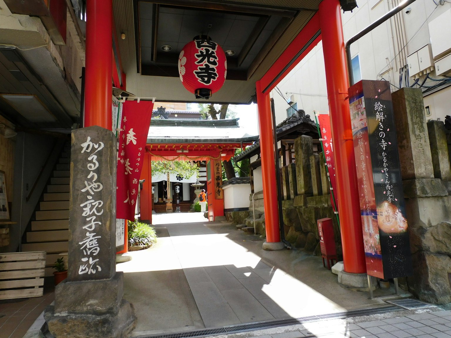 Entrance of a temple featuring red torii gates and decorative banners