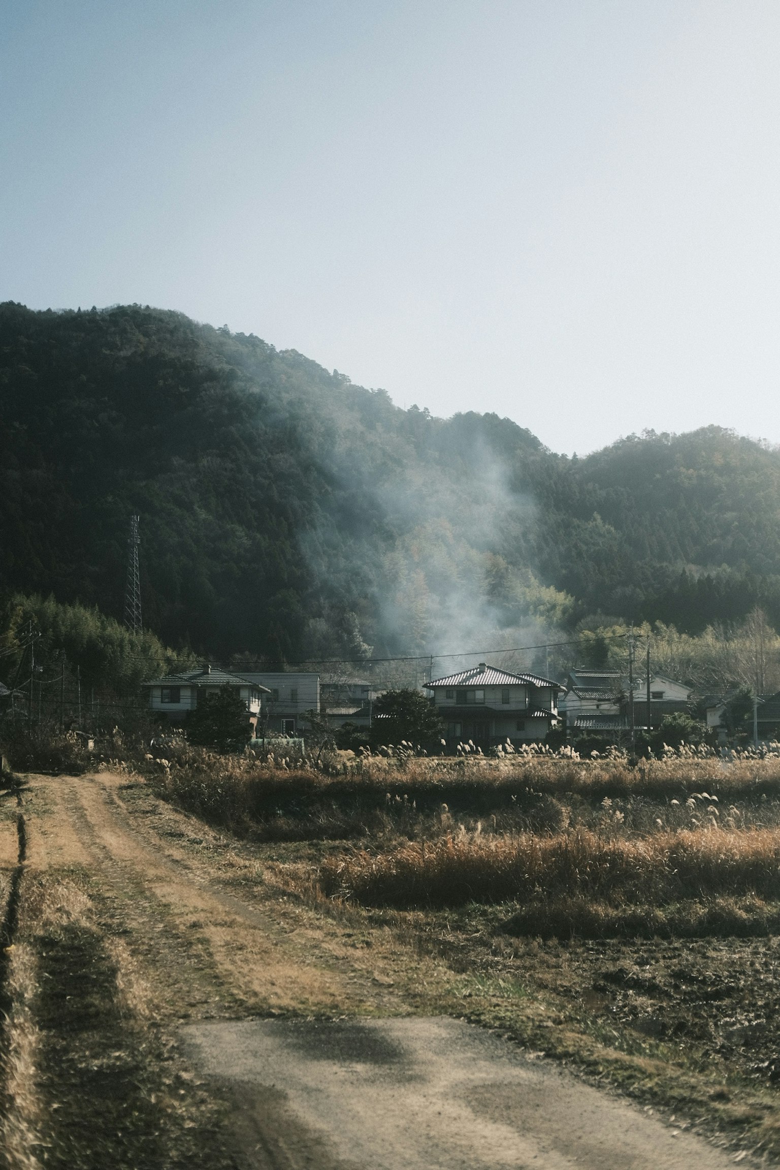 Un paisaje rural con humo que se eleva de un pueblo en las montañas