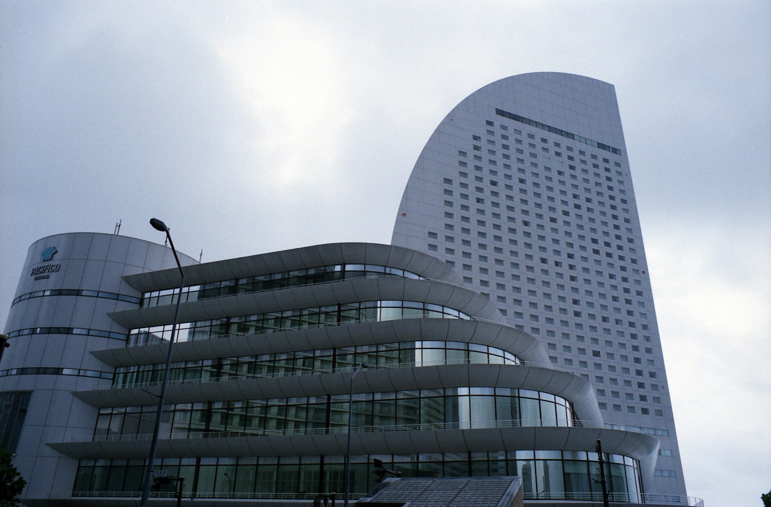 Modern building exterior with curved design glass facade and cloudy sky