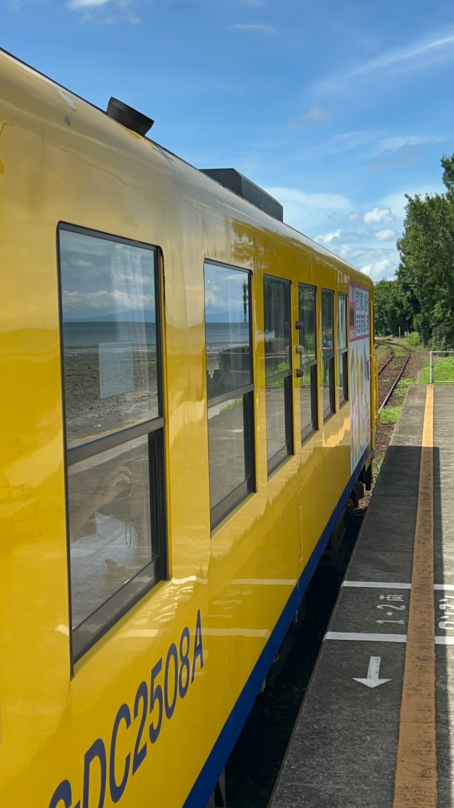 Kereta kuning di stasiun dengan aksen biru dan langit cerah
