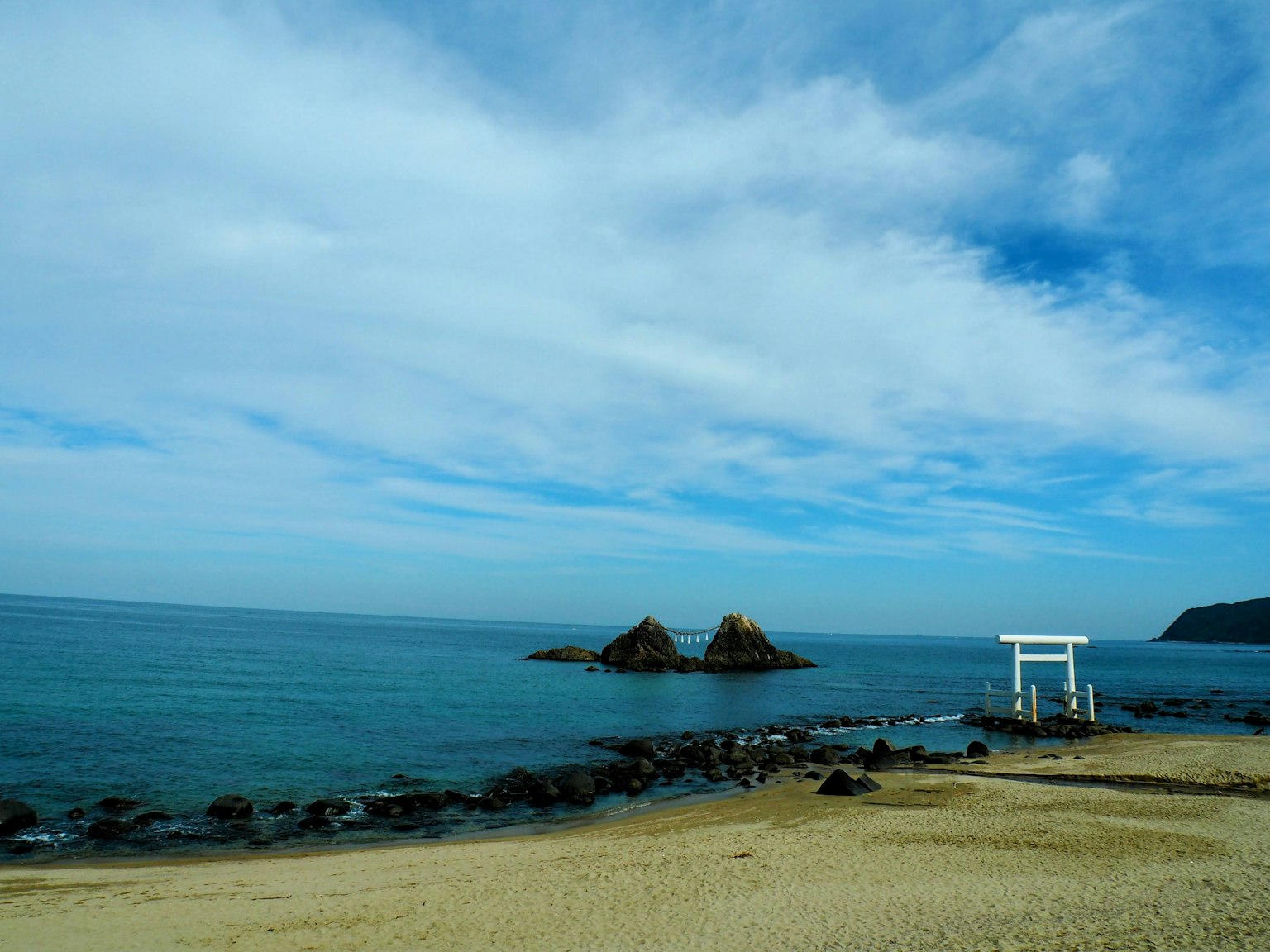 Vista de playa serena con mar tranquilo y puerta torii blanca