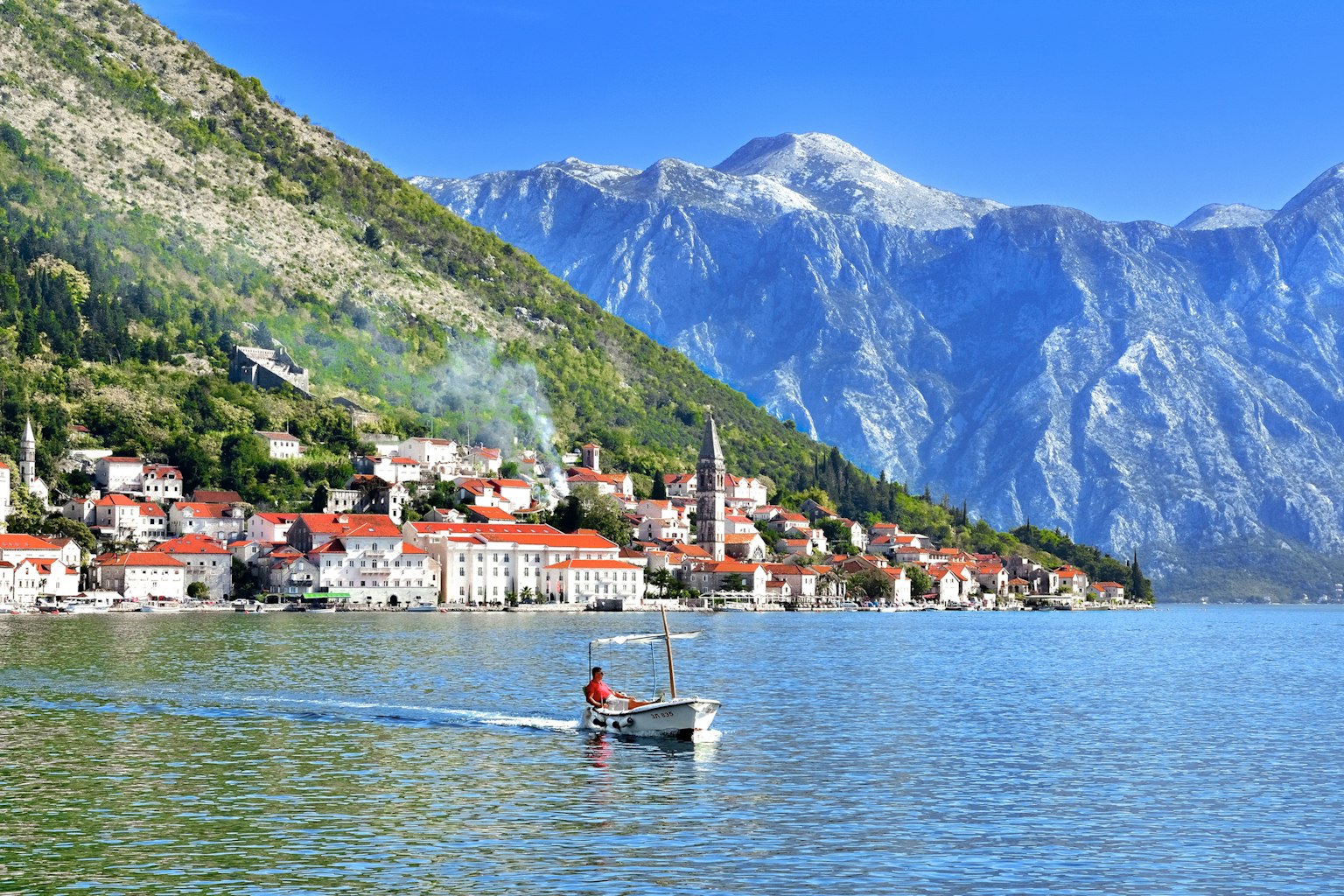 Malersiche Ansicht von Bergen und blauem See mit einem kleinen Boot