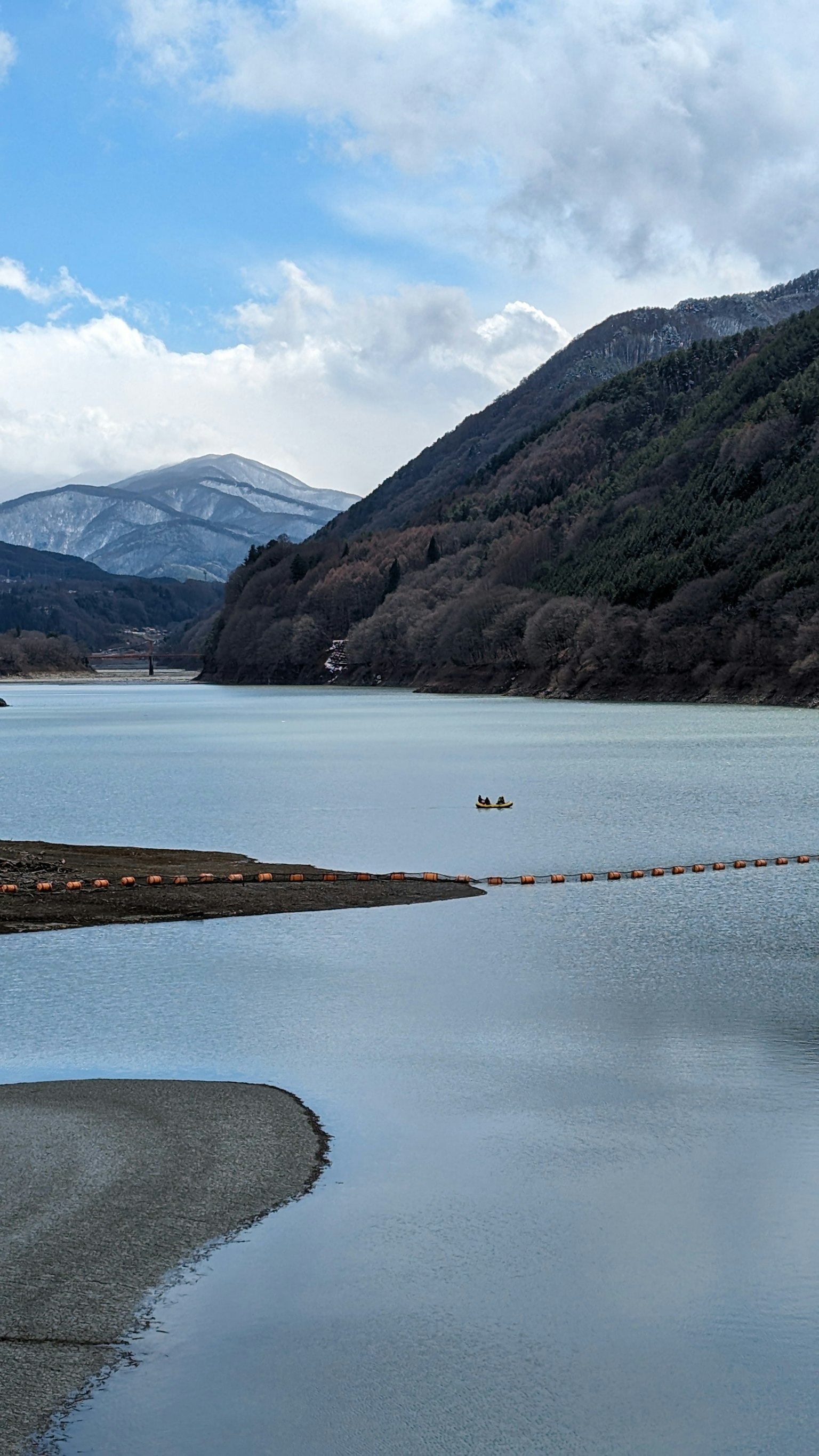 Calm lake surrounded by mountains blue sky and white clouds