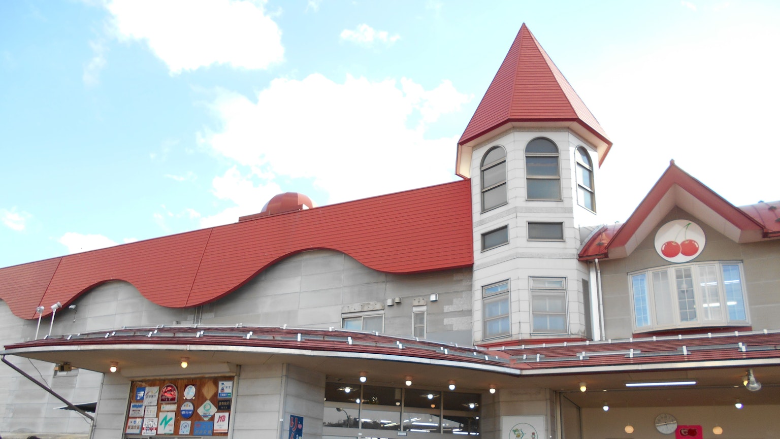 Esterno di un edificio con tetto rosso e torre sotto un cielo blu
