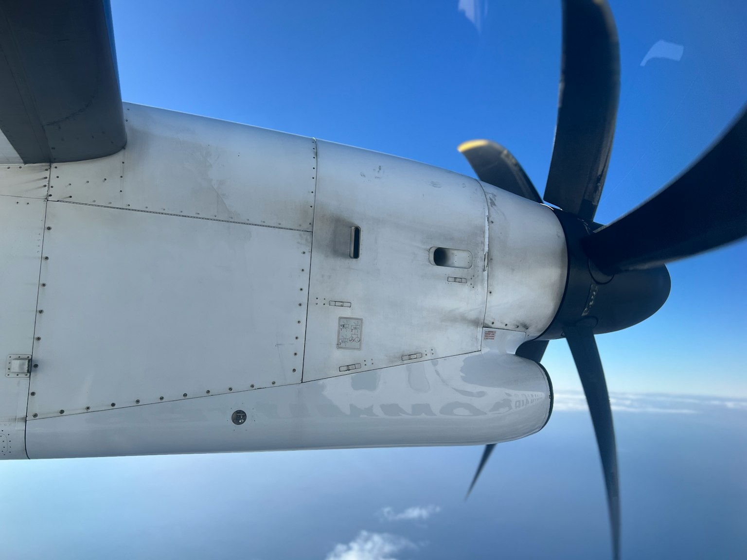 Aircraft propeller and wing section visible against a blue sky
