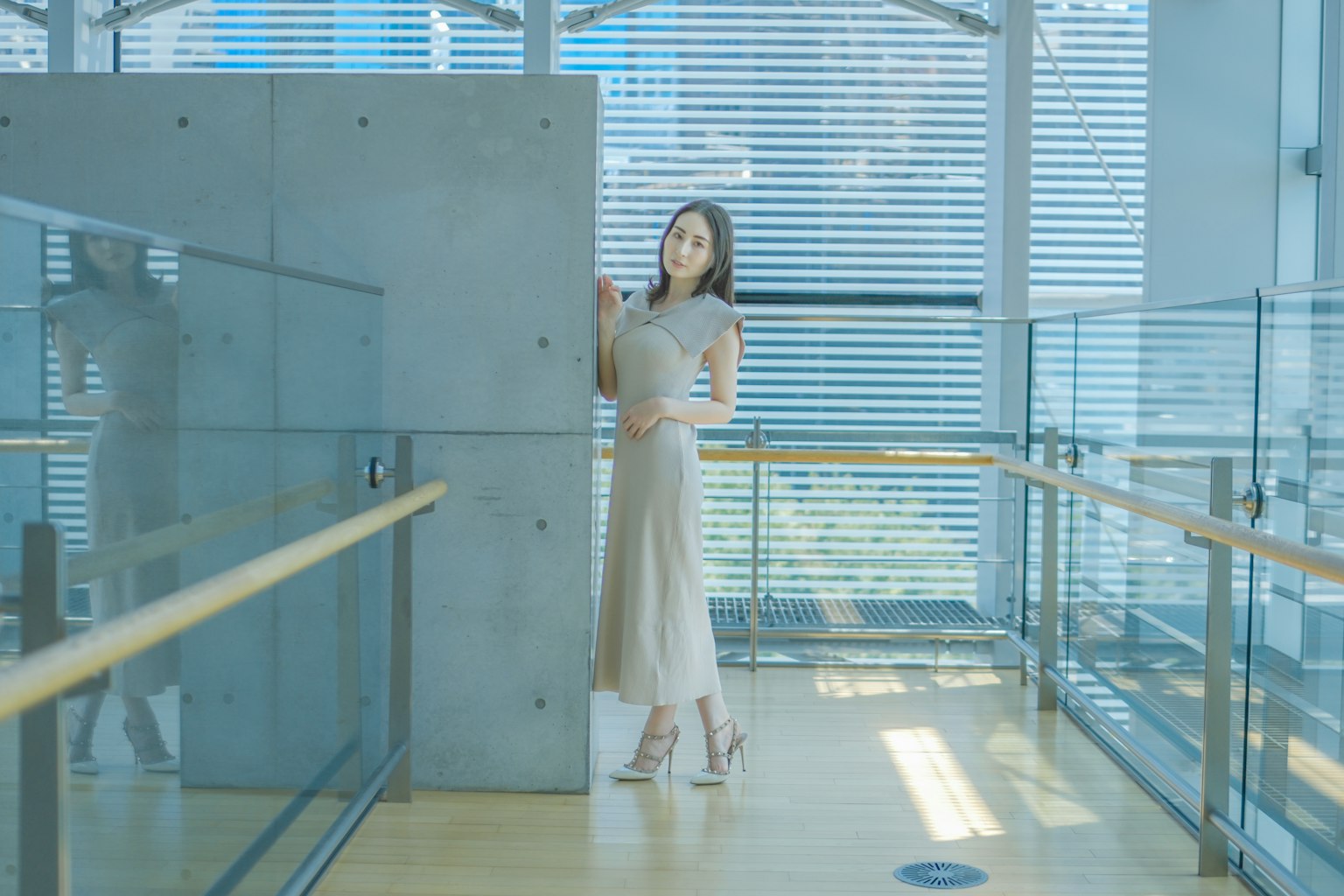 女性站在現代建築中，旁邊有玻璃欄杆