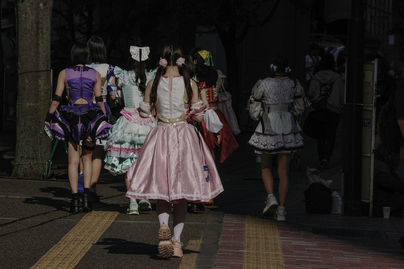 Gruppo di cosplayer che cammina all'indietro in costumi colorati su una strada poco illuminata