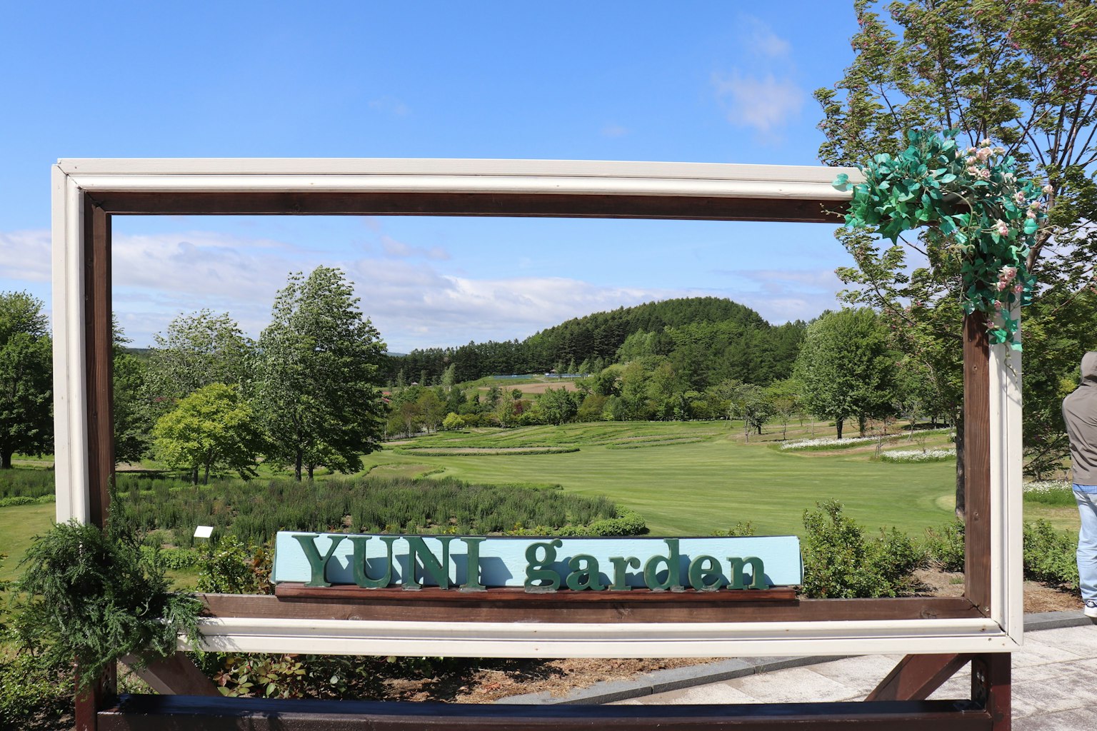 A beautiful garden scene framed with greenery and a sign that reads Vine Garden