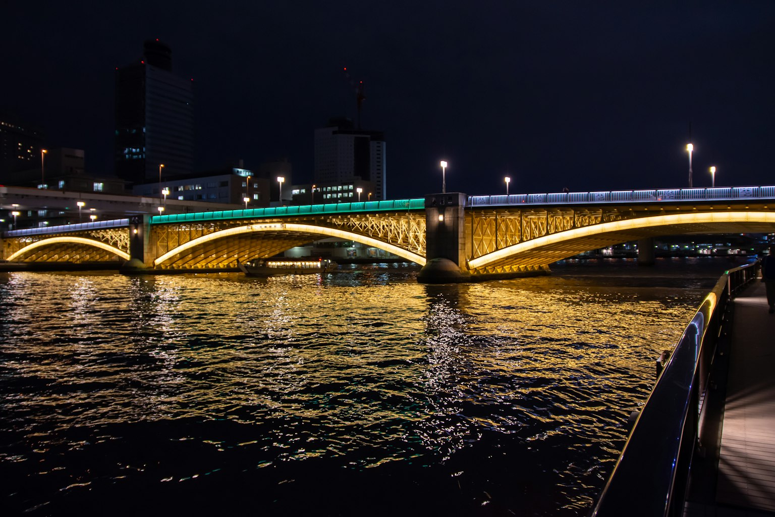 Pont brillamment éclairé au-dessus de la rivière la nuit avec des reflets sur l'eau