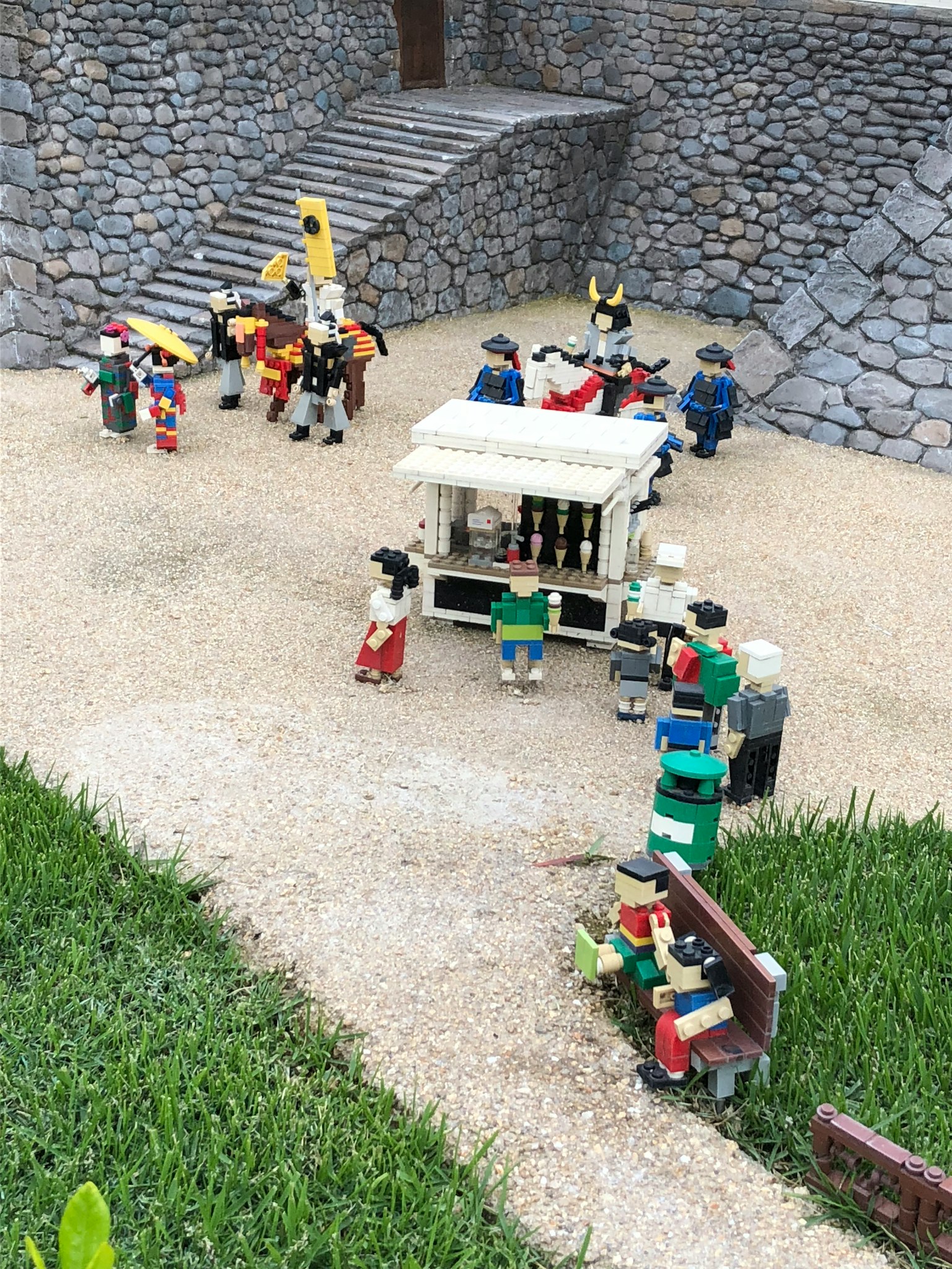 Una scena di figure LEGO riunite in una piazza con un chiosco e scale