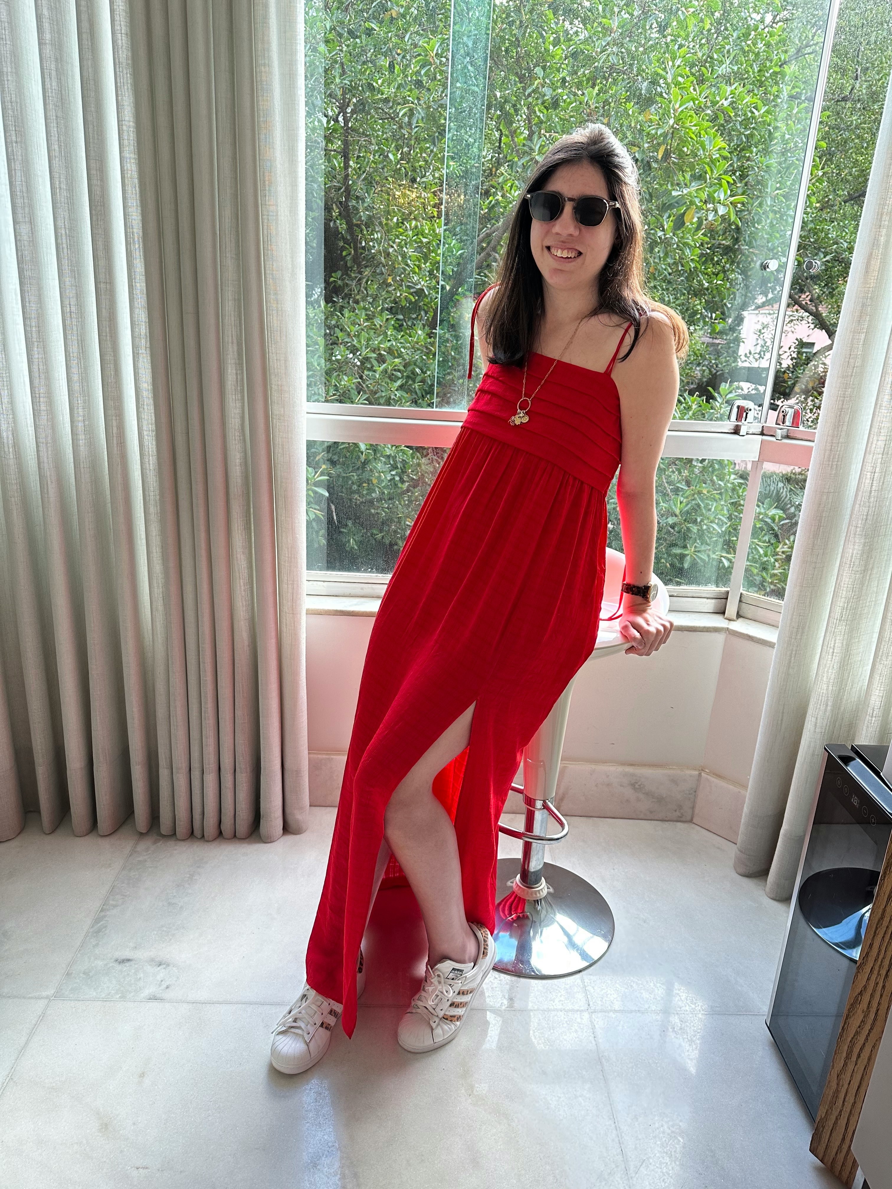 窓辺で赤いロングワンピースを着た女性の立ち姿