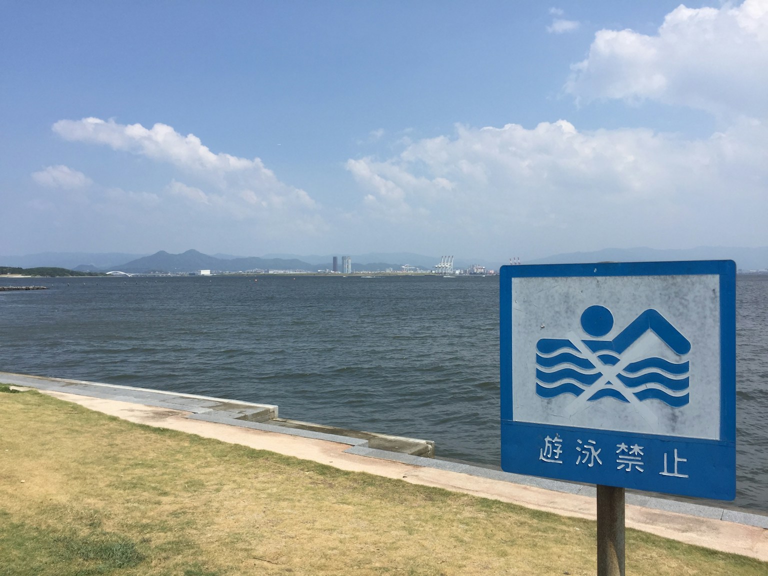 Papan larangan berenang biru dengan pemandangan laut