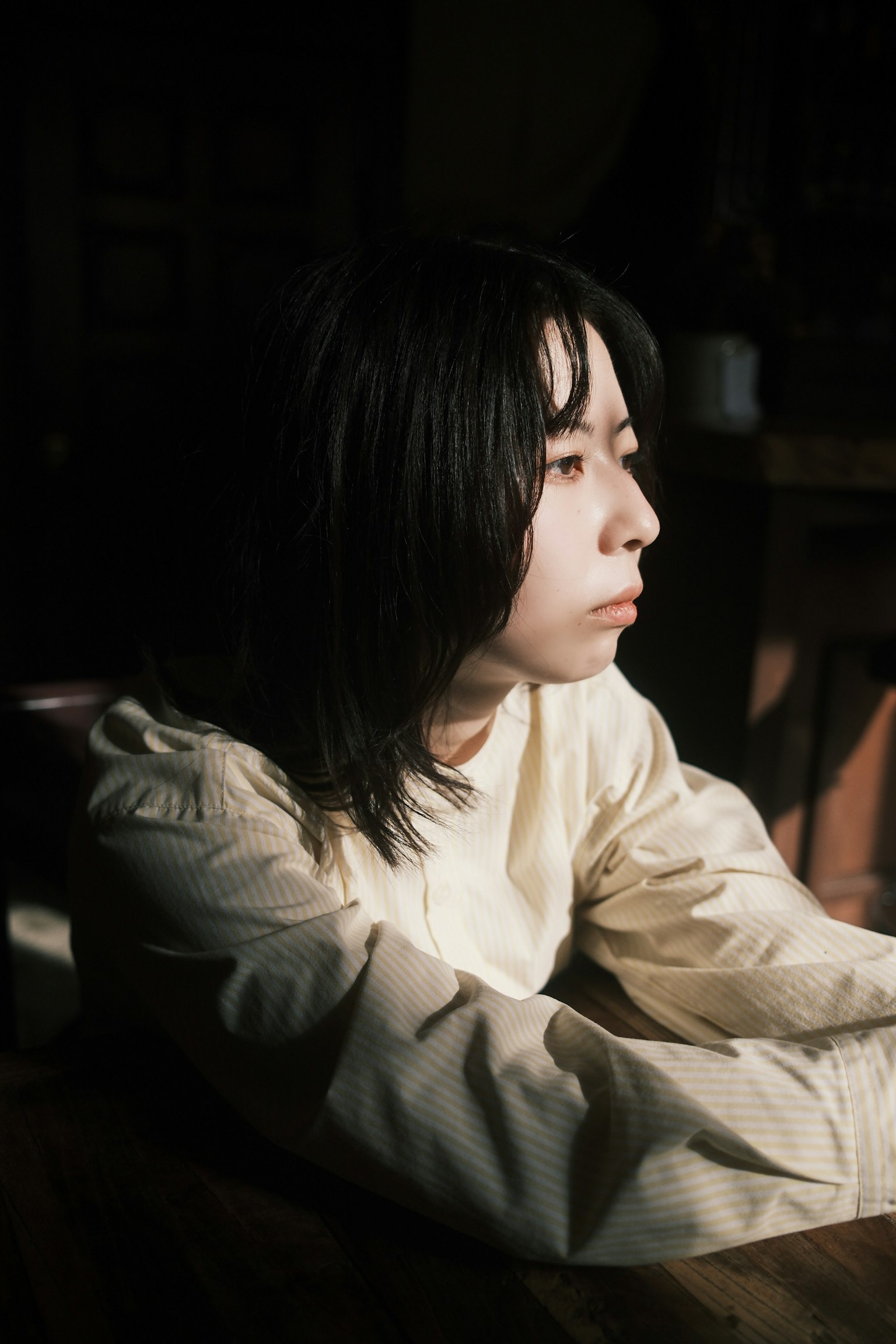 薄暗い部屋で考え込む若い女性の横顔