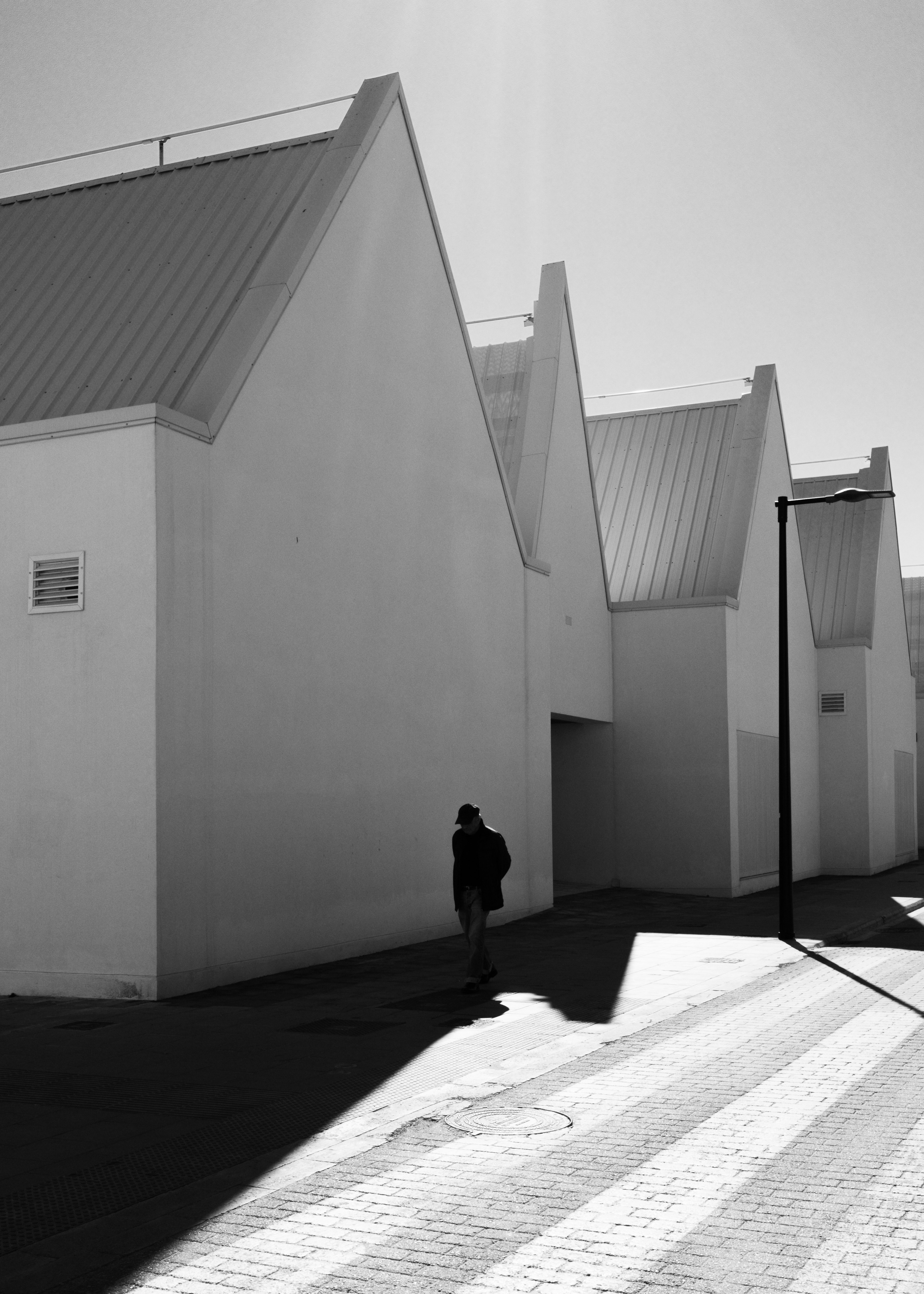 pasillo exterior con paredes blancas y edificios modernos de líneas angulares