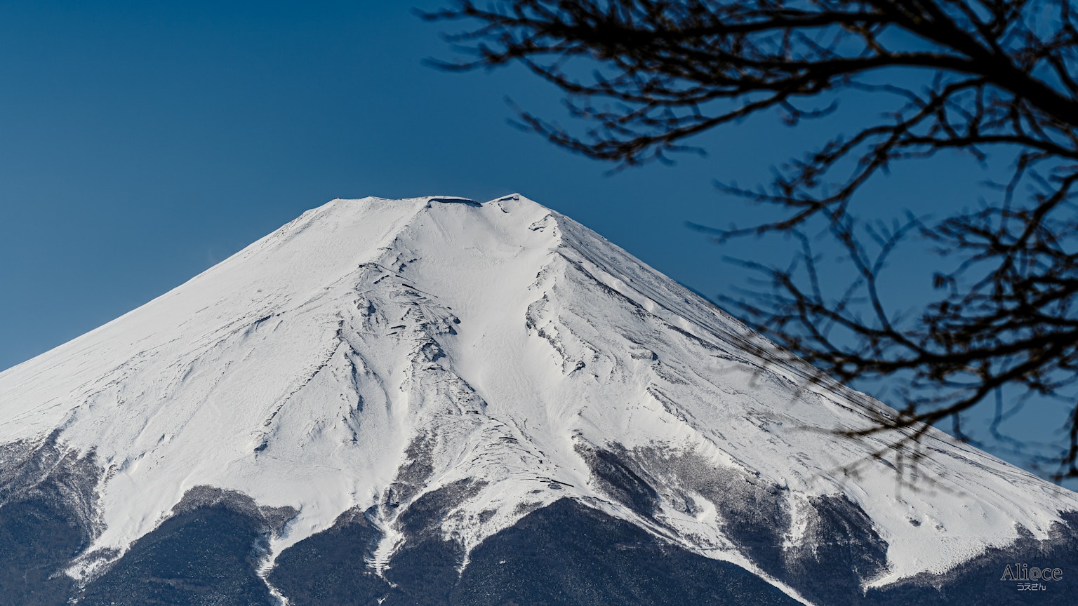 Snow-covered peak of Mount Fuji against a clear blue sky