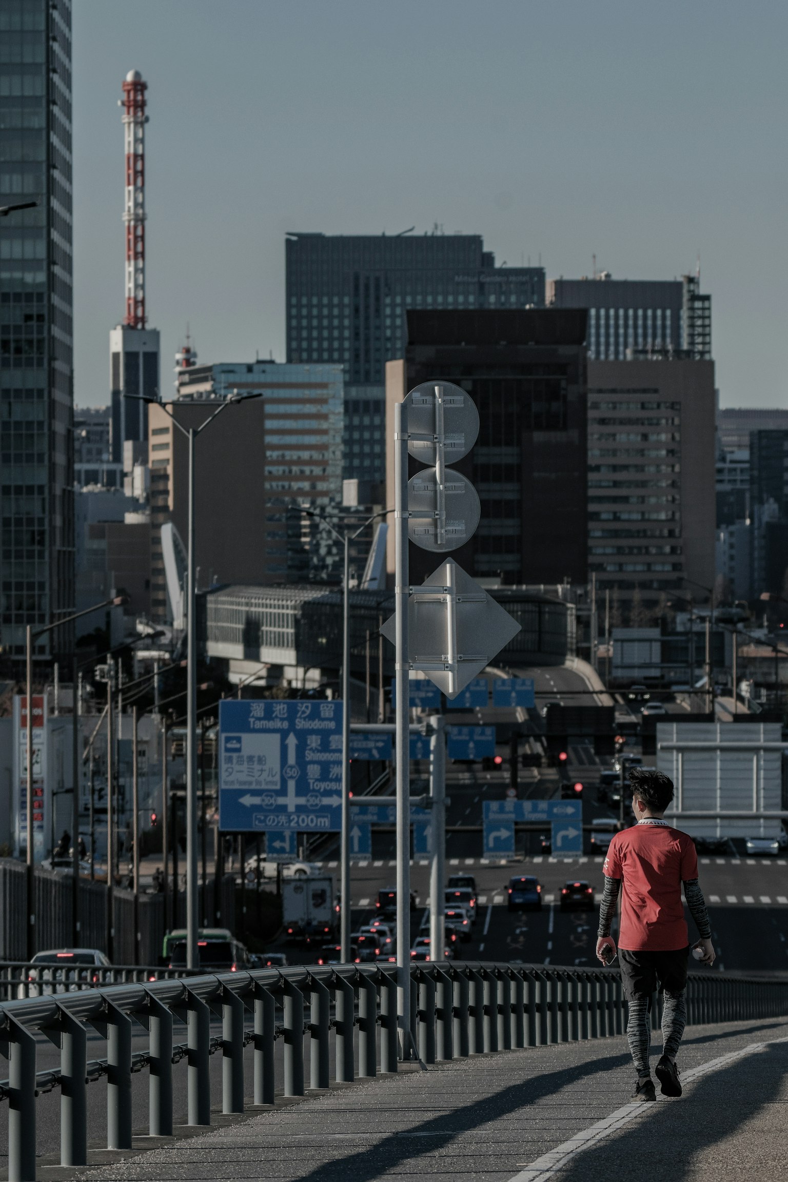 Une personne marchant à Tokyo avec des gratte-ciel et une tour de communication en arrière-plan