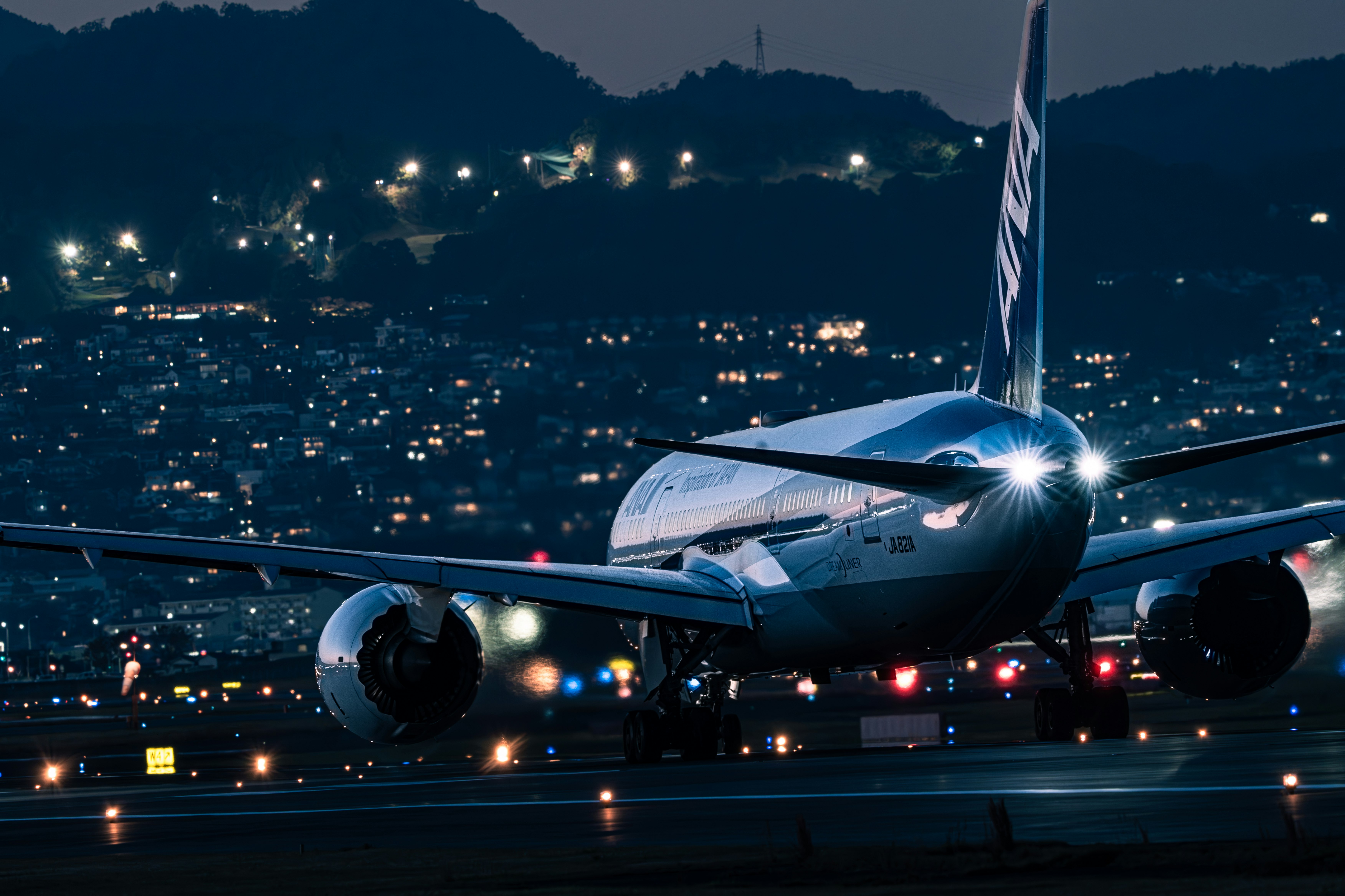 Aereo di linea fermo su una pista notturna con skyline cittadino