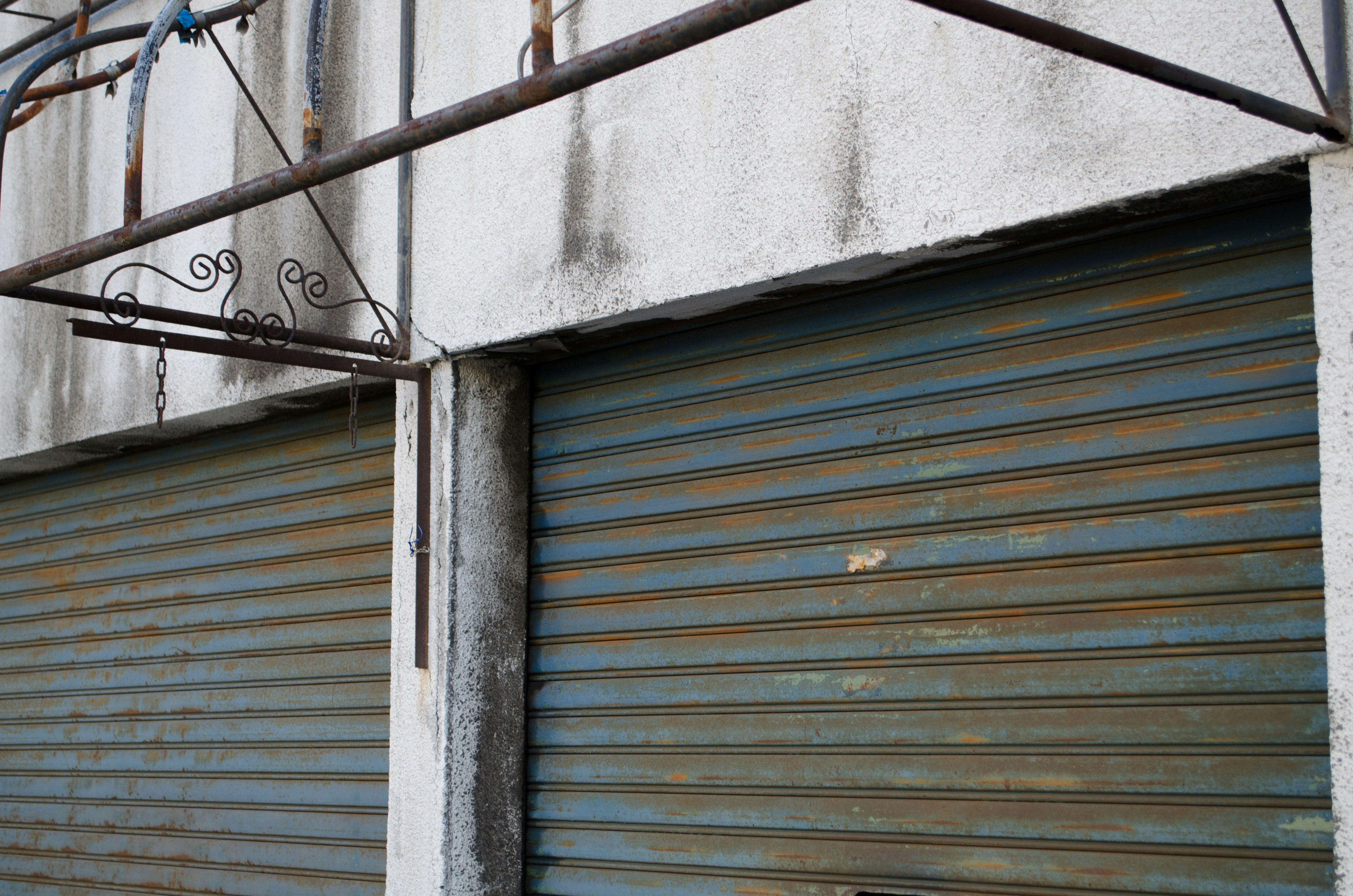 metal railing beside a shuttered wall