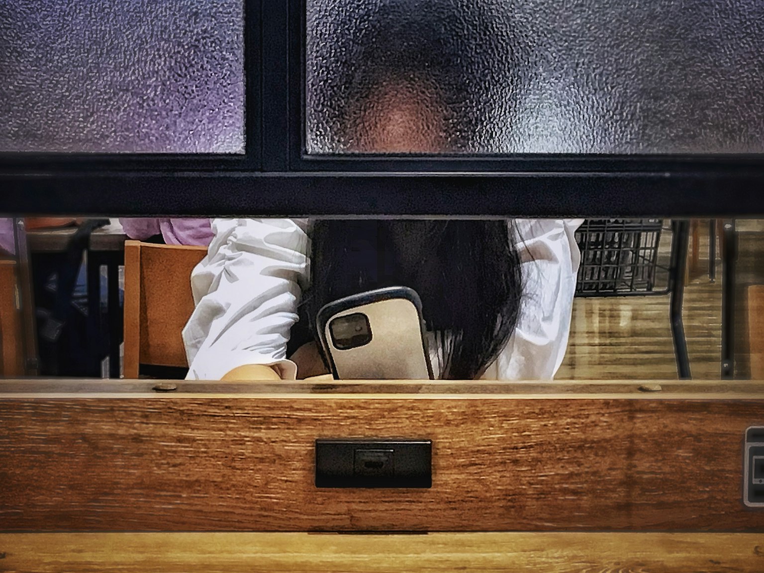 Orang yang memegang smartphone terlihat melalui kaca buram