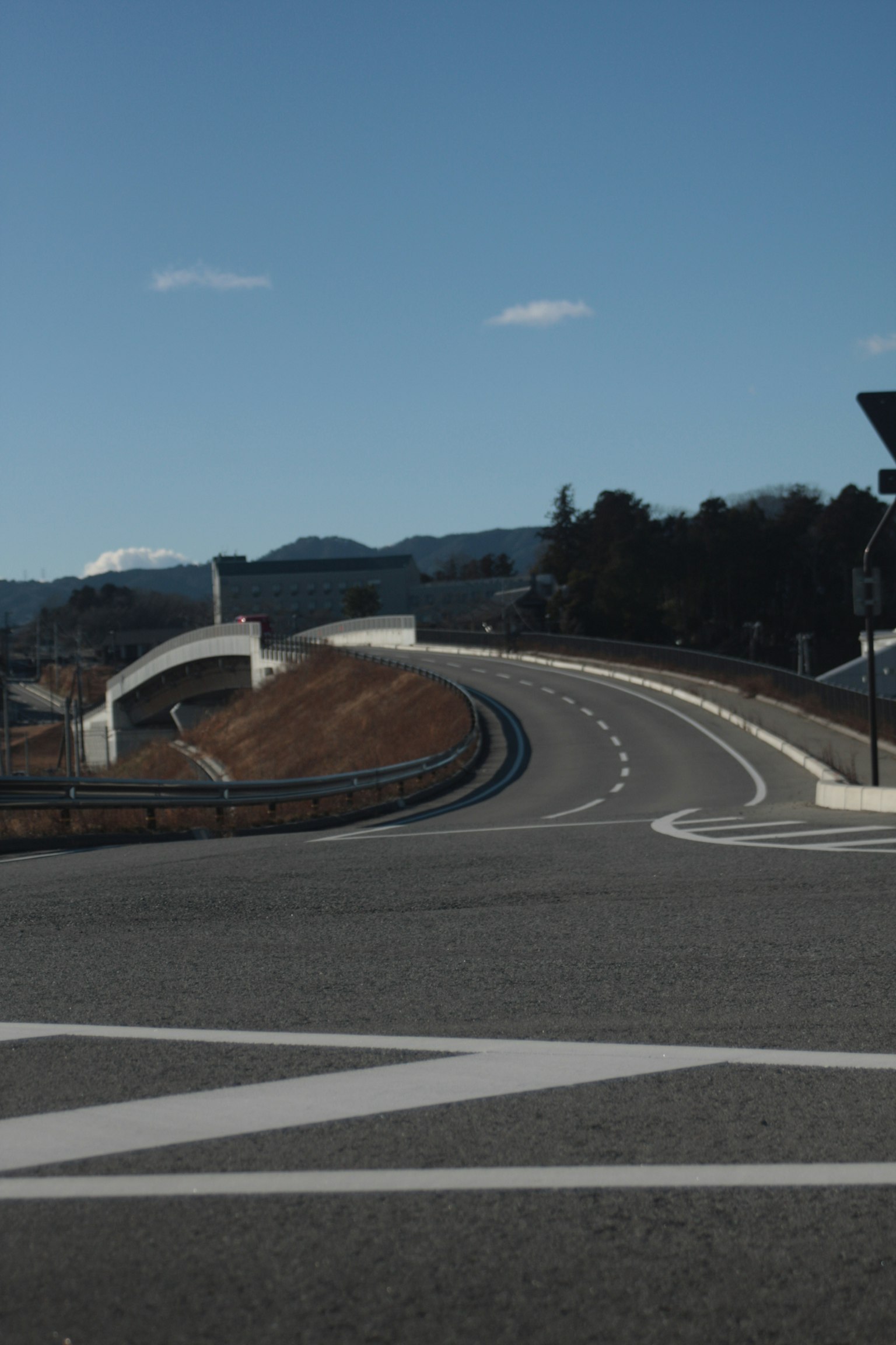 Kurvige Straße mit einer Brücke unter einem klaren blauen Himmel