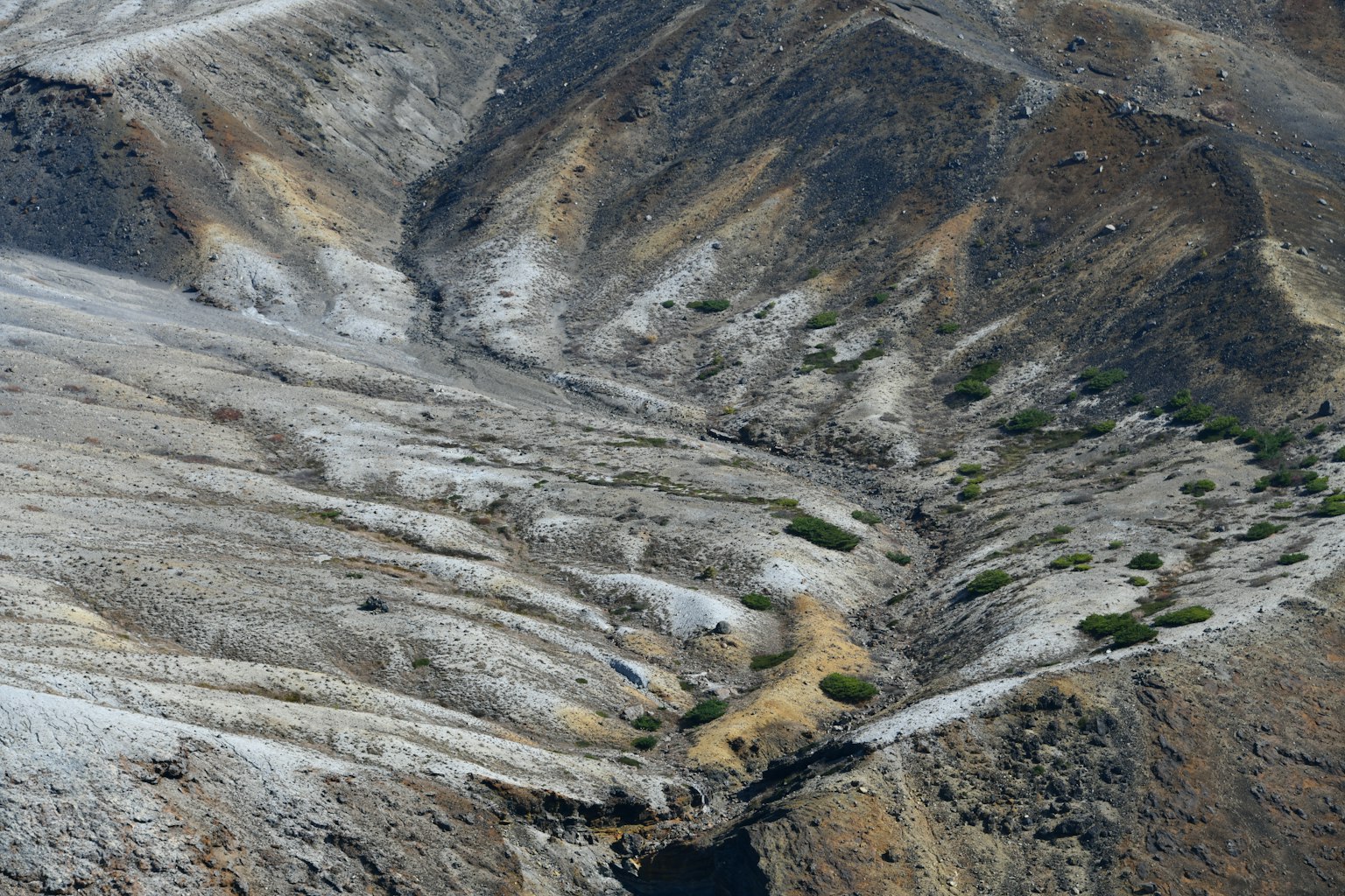 Vista aerea di pendii montuosi secchi e una valle con vegetazione verde sparsa
