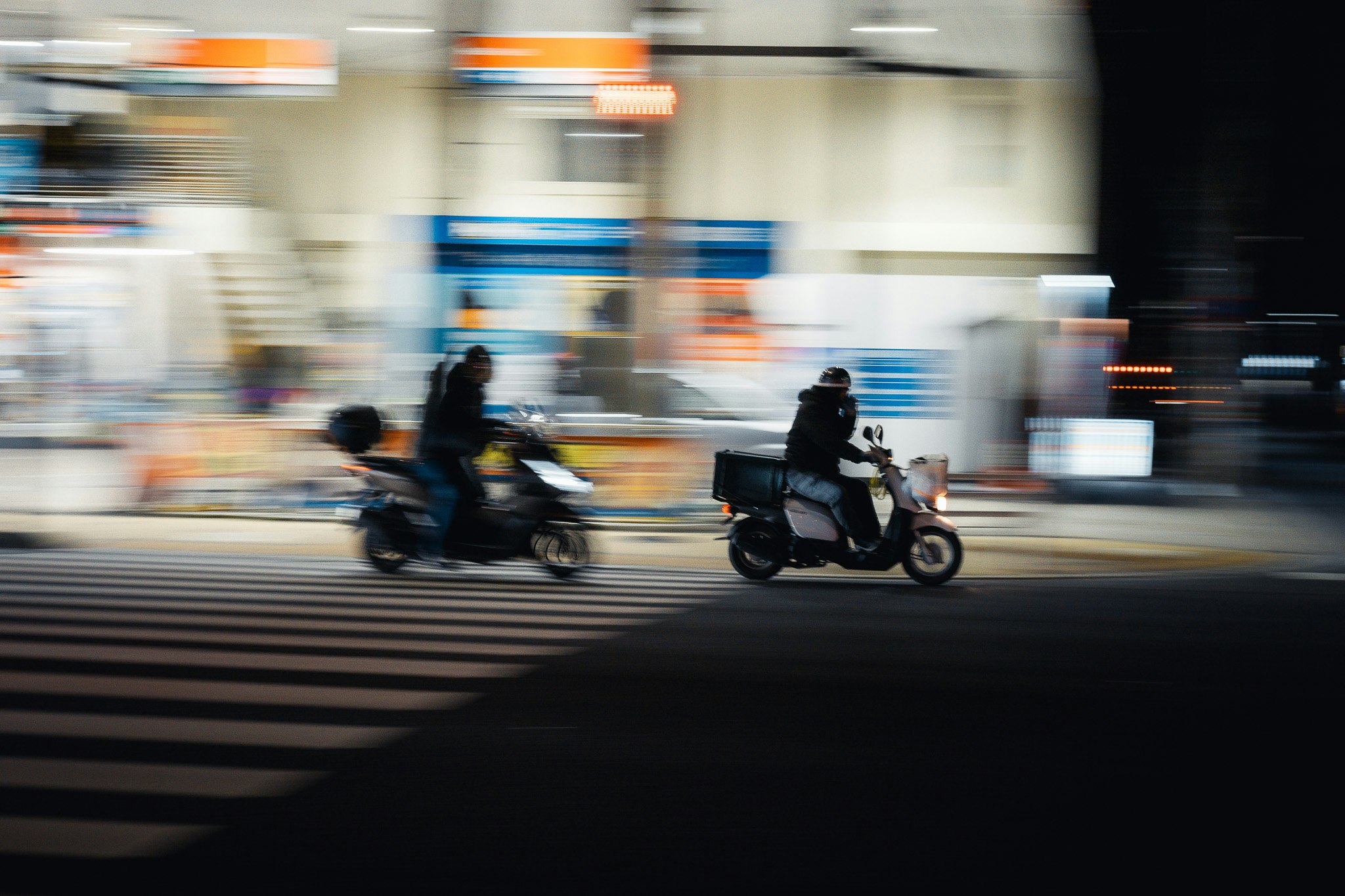 バイクとスクーターが走る街の交差点の流し撮り