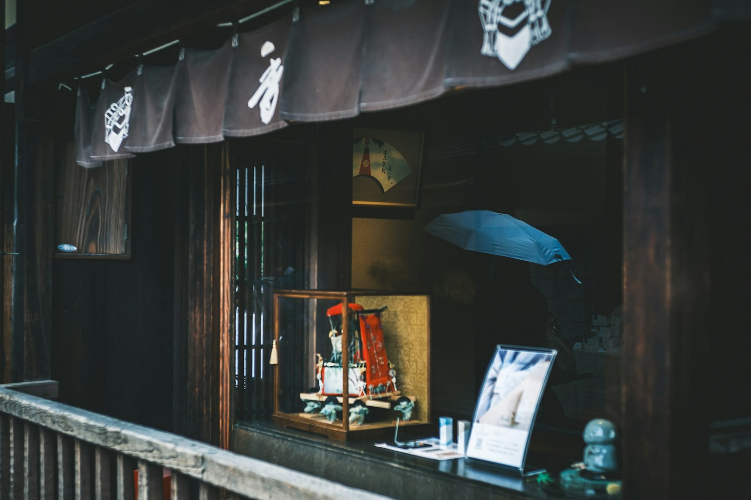 Vista exterior de la ventana de una tienda japonesa tradicional con muñecas coloridas y un paraguas