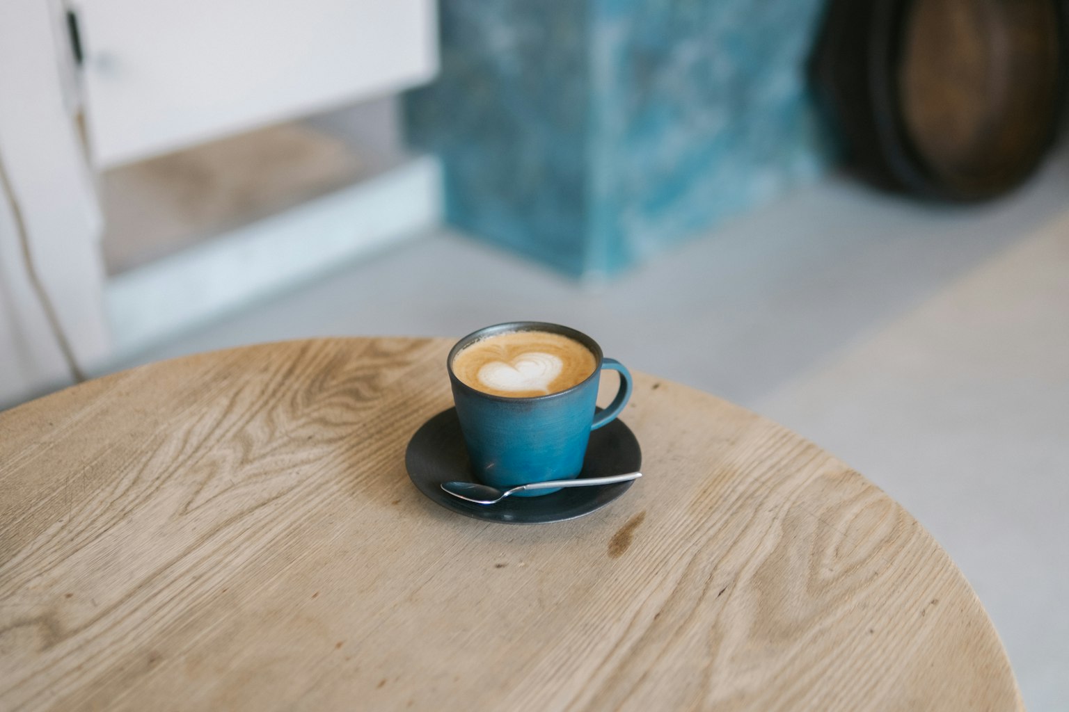 Kopi latte dengan seni di atas dalam cangkir biru di atas meja kayu