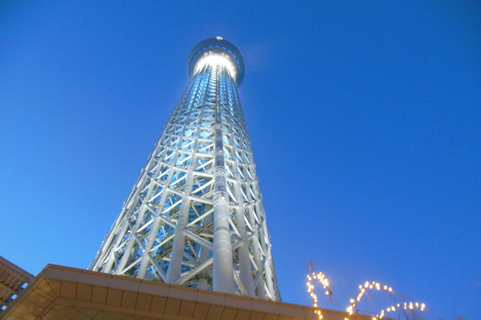 Tokyo Skytree di malam hari dengan latar belakang langit biru menampilkan ketinggian dan pencahayaannya