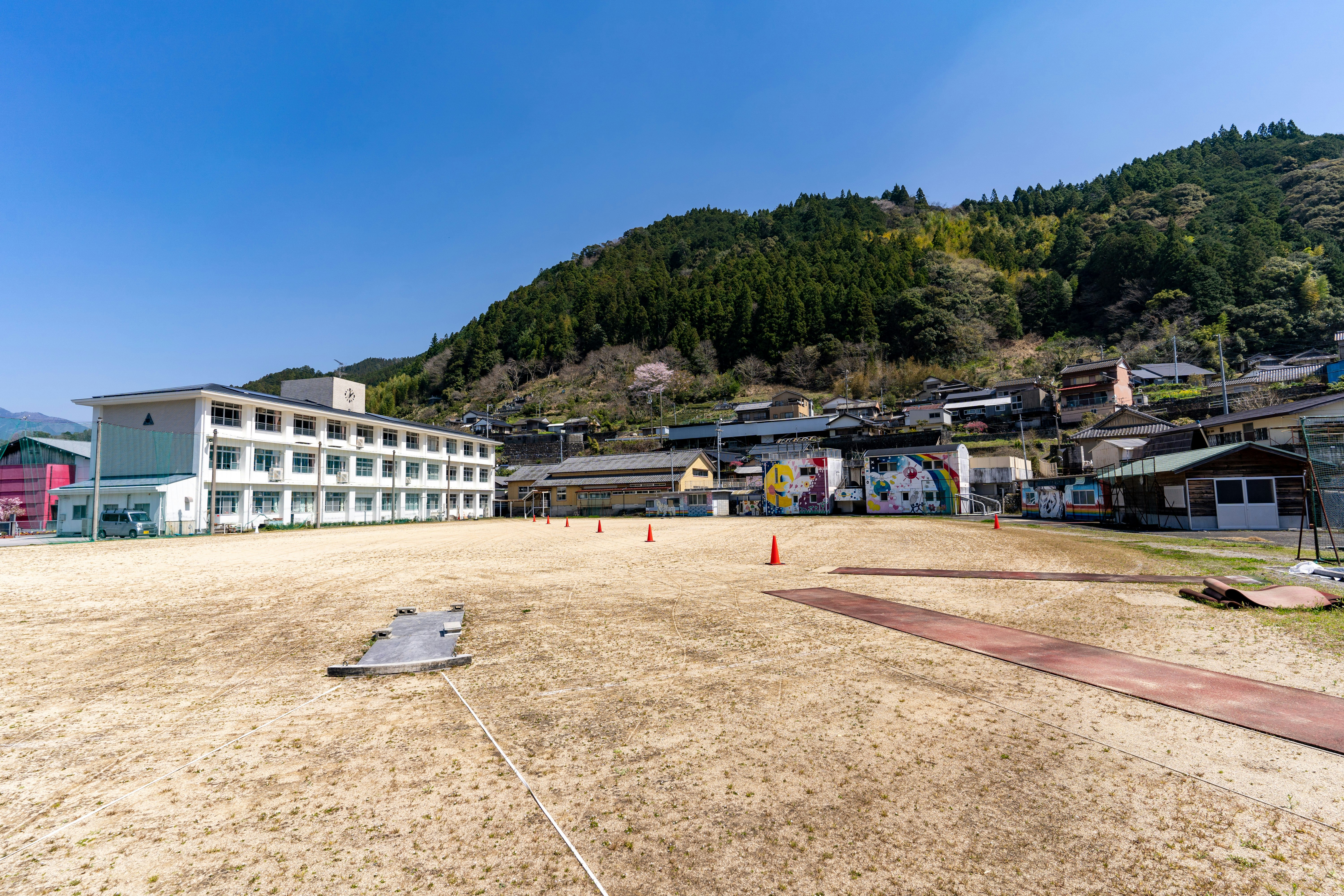 山の麓にある校舎と運動場の風景