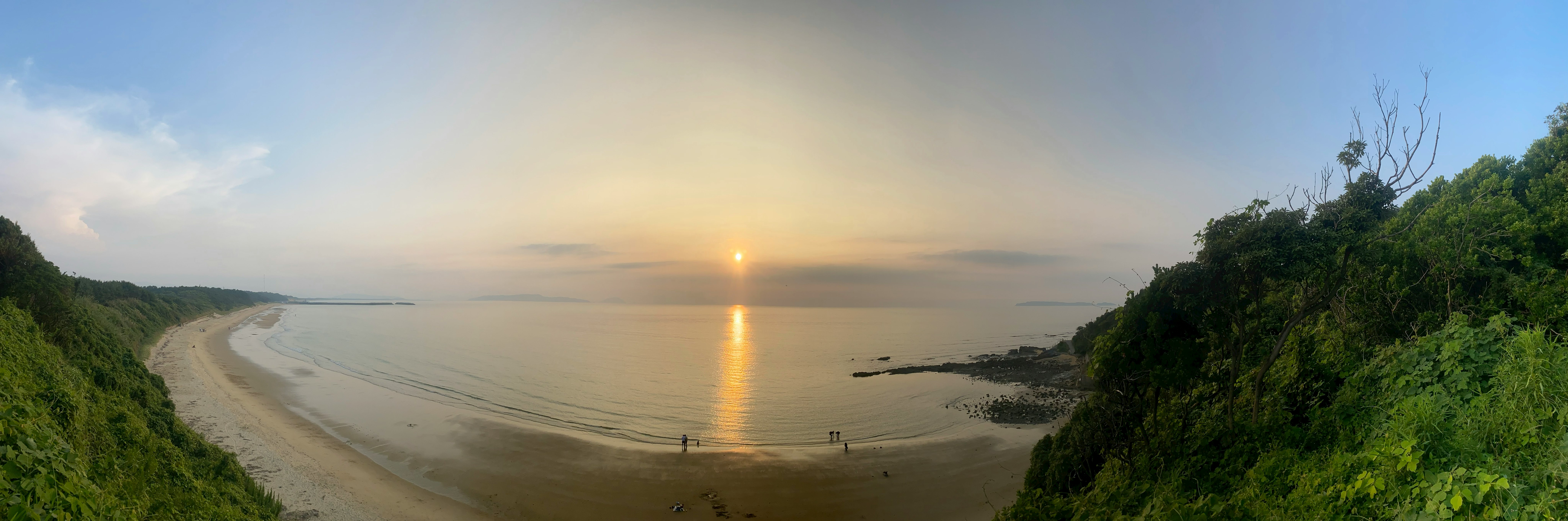 sunset beach and sandy shoreline framed by green headlands