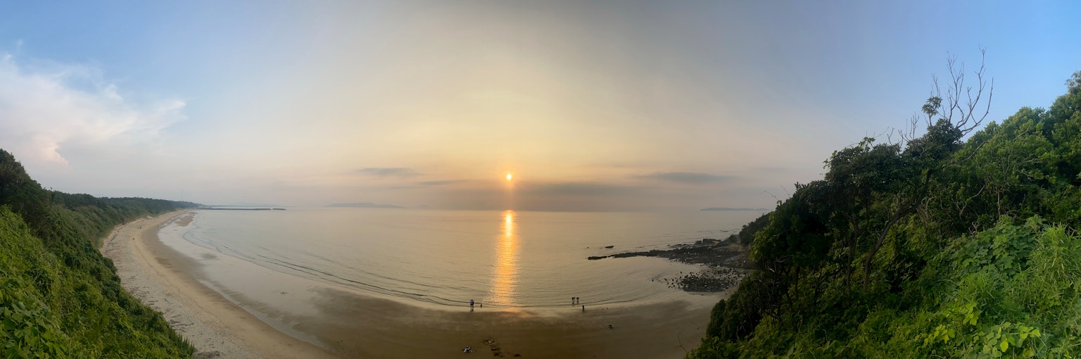 Vue panoramique d'un beau coucher de soleil reflété sur la mer collines verdoyantes à côté de la côte